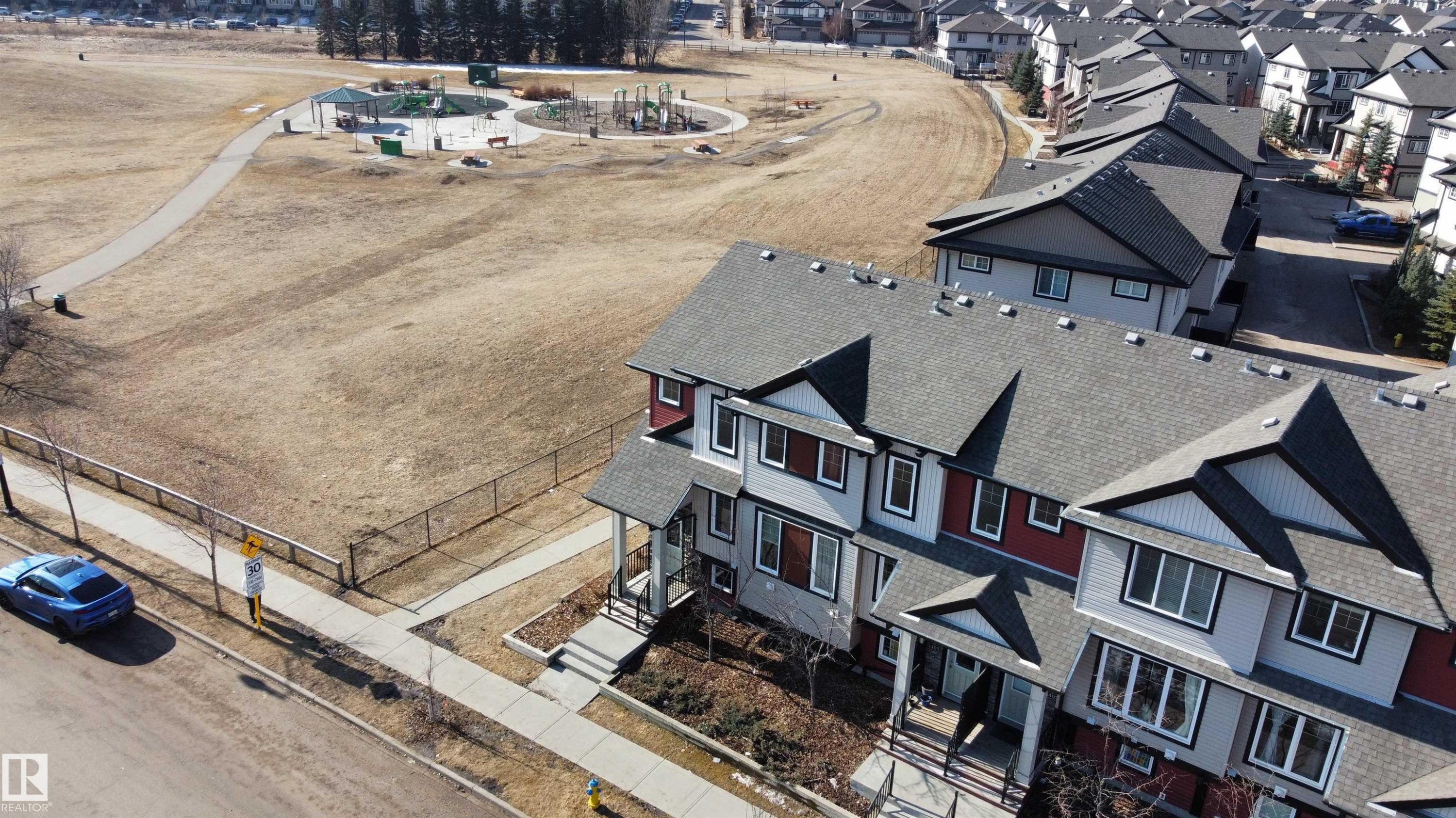The property features a multi-level roofline and is situated near a park with walking paths and playground equipment - 1403 Cunningham Drive, Edmonton, AB - Outdoor