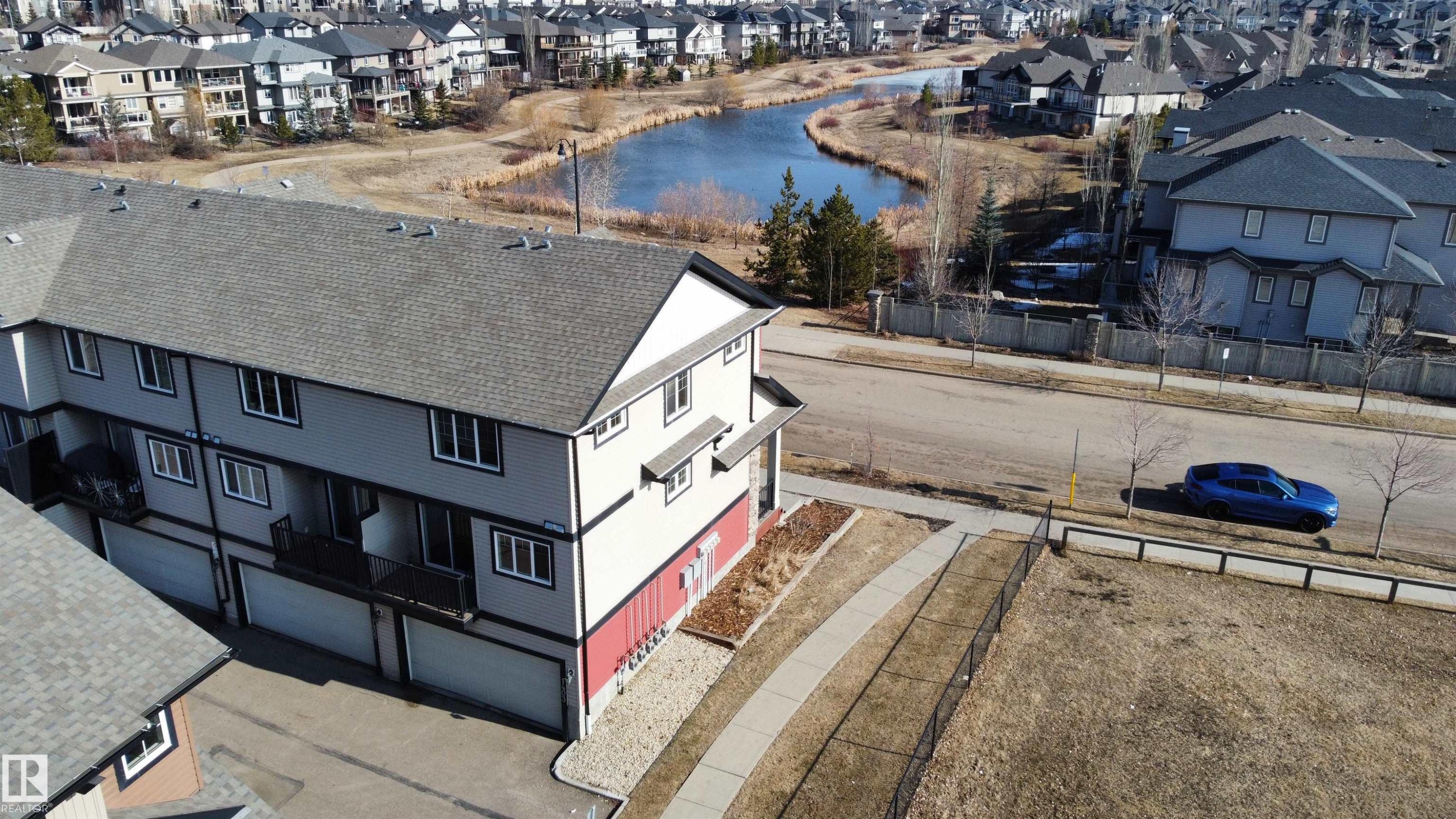 This property features a multi-story exterior with a gray roof and light-colored siding, accented by dark trim around the windows - 1403 Cunningham Drive, Edmonton, AB - Outdoor