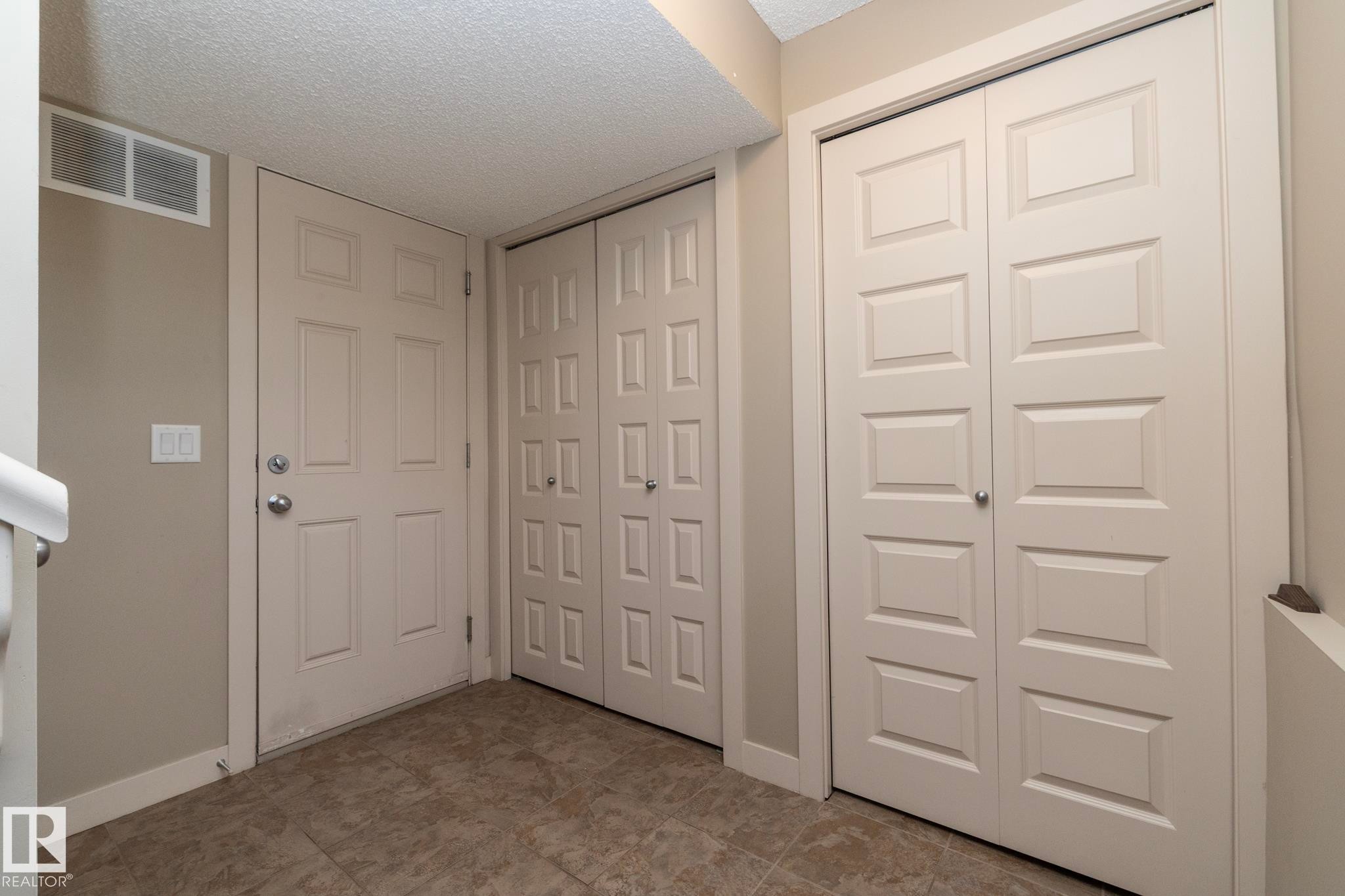 Entryway featuring tiled flooring, a paneled door, and two paneled closet doors - 1403 Cunningham Drive, Edmonton, AB - Indoor Photo Showing Other Room