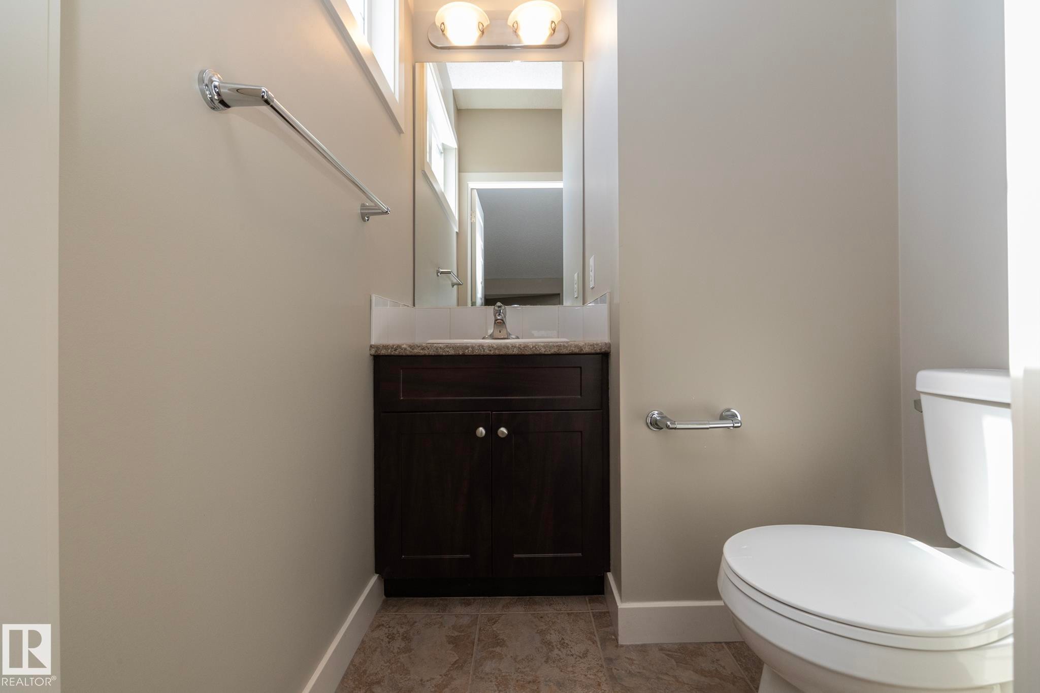Bathroom featuring a vanity with a dark wood cabinet, a light-colored countertop, and a mirror with overhead lighting - 1403 Cunningham Drive, Edmonton, AB - Indoor Photo Showing Bathroom