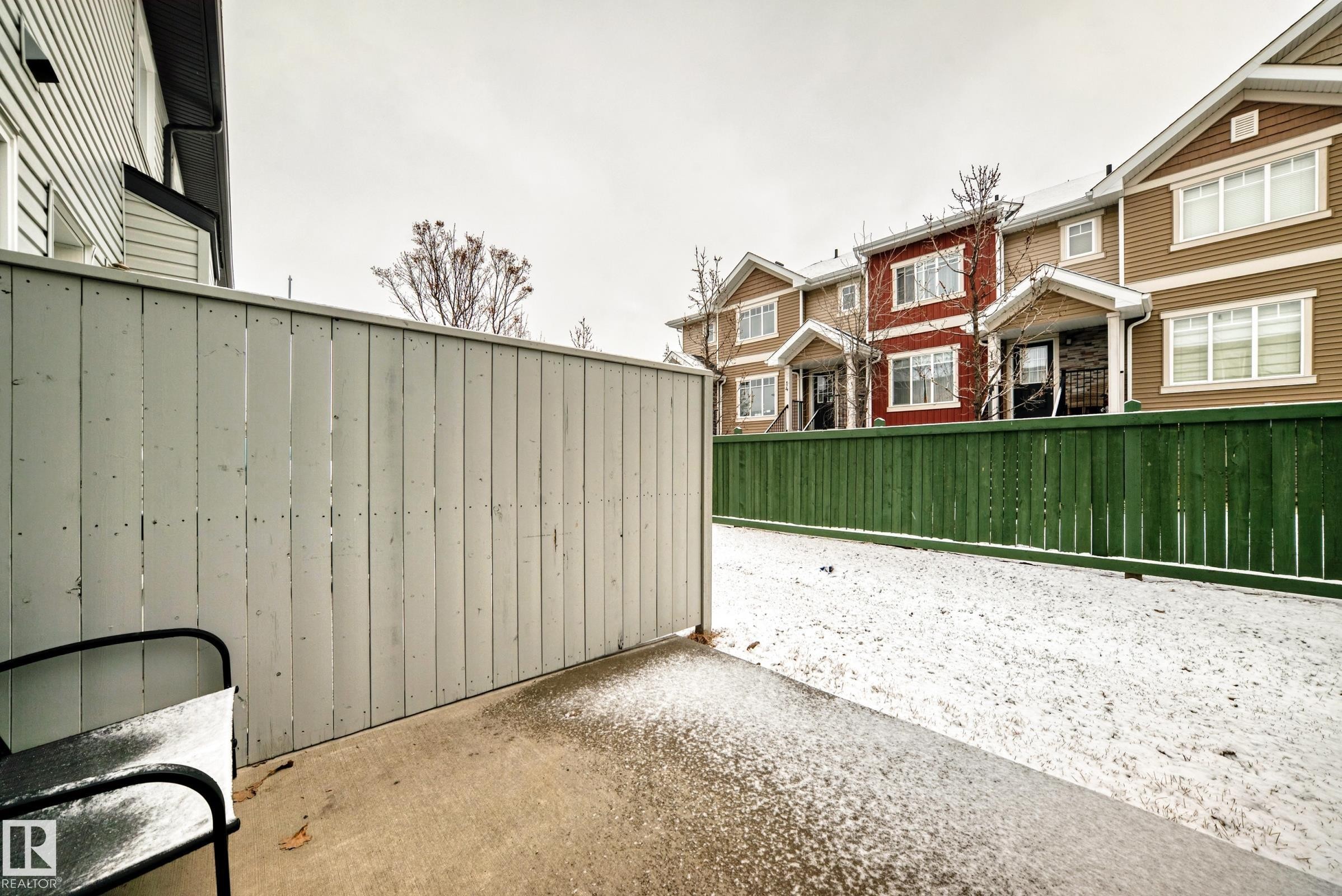 The property features a private patio area with a light-colored privacy fence - 8 13838 166Ave, Edmonton, AB - Outdoor With Exterior