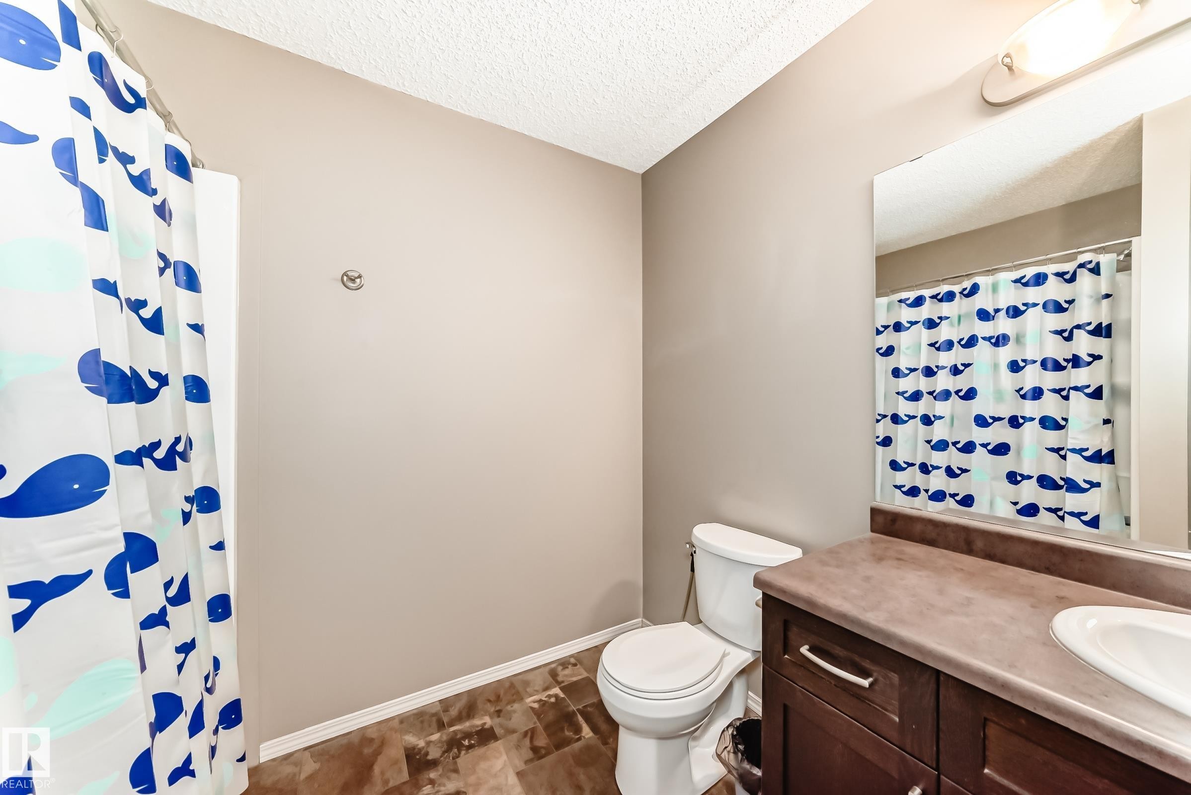 Bathroom featuring a vanity with a sink, a toilet, and a shower with a curtain - 8 13838 166Ave, Edmonton, AB - Indoor Photo Showing Bathroom