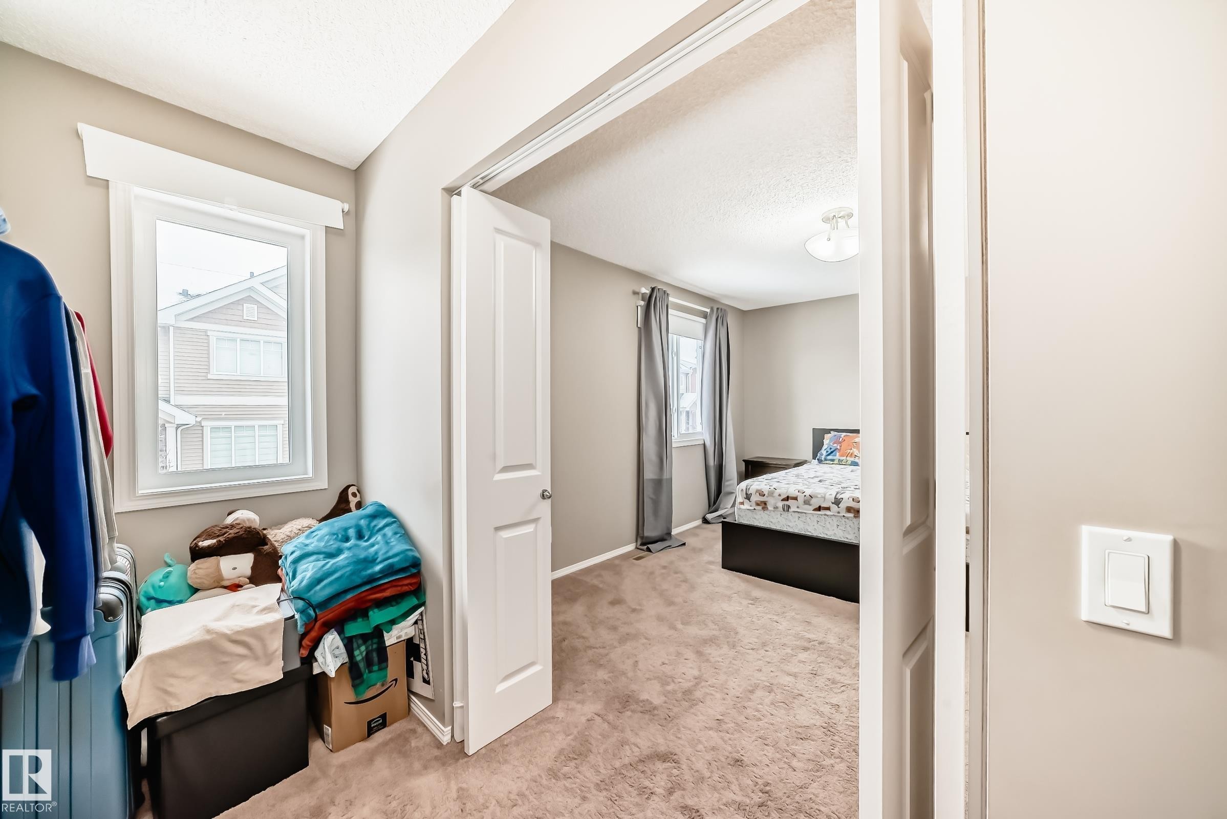 This room features a window with white trim, a neutral wall color, and carpeted flooring - 8 13838 166Ave, Edmonton, AB - Indoor Photo Showing Bedroom
