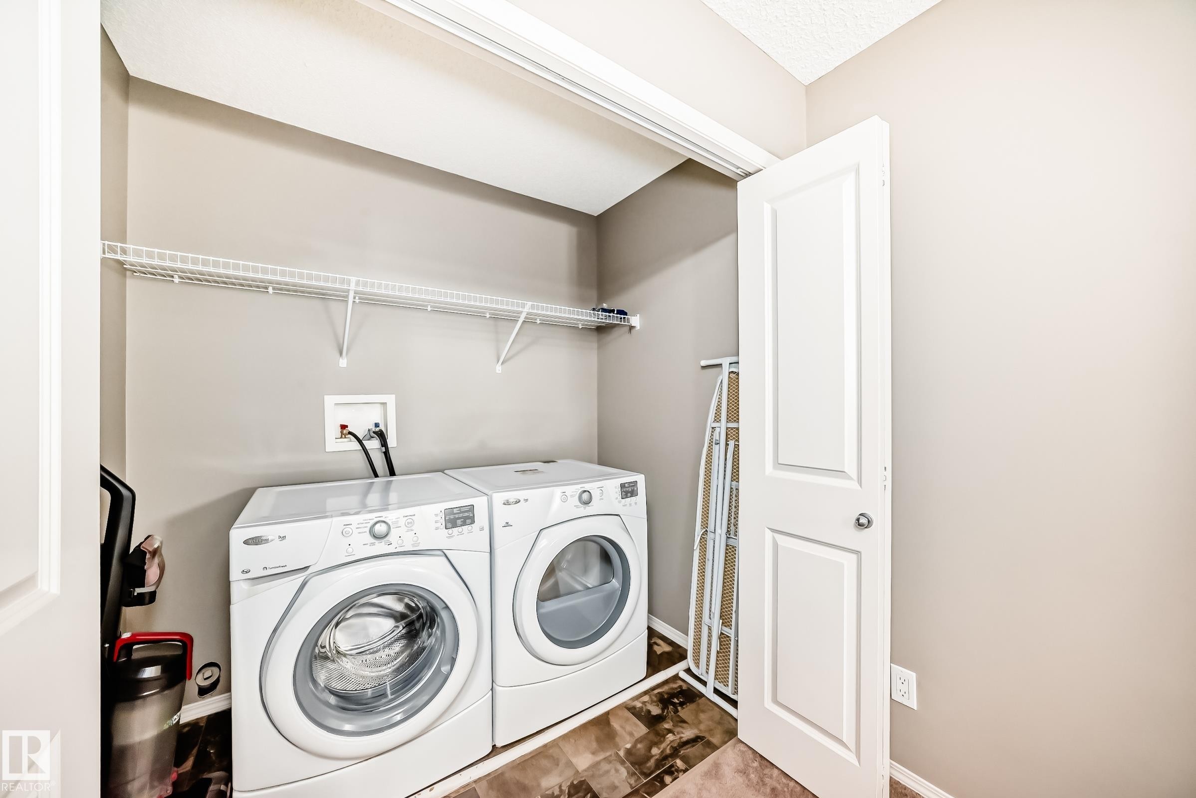 Dedicated laundry area featuring a washer and dryer, a wire shelving unit, and tiled flooring - 8 13838 166Ave, Edmonton, AB - Indoor Photo Showing Laundry Room