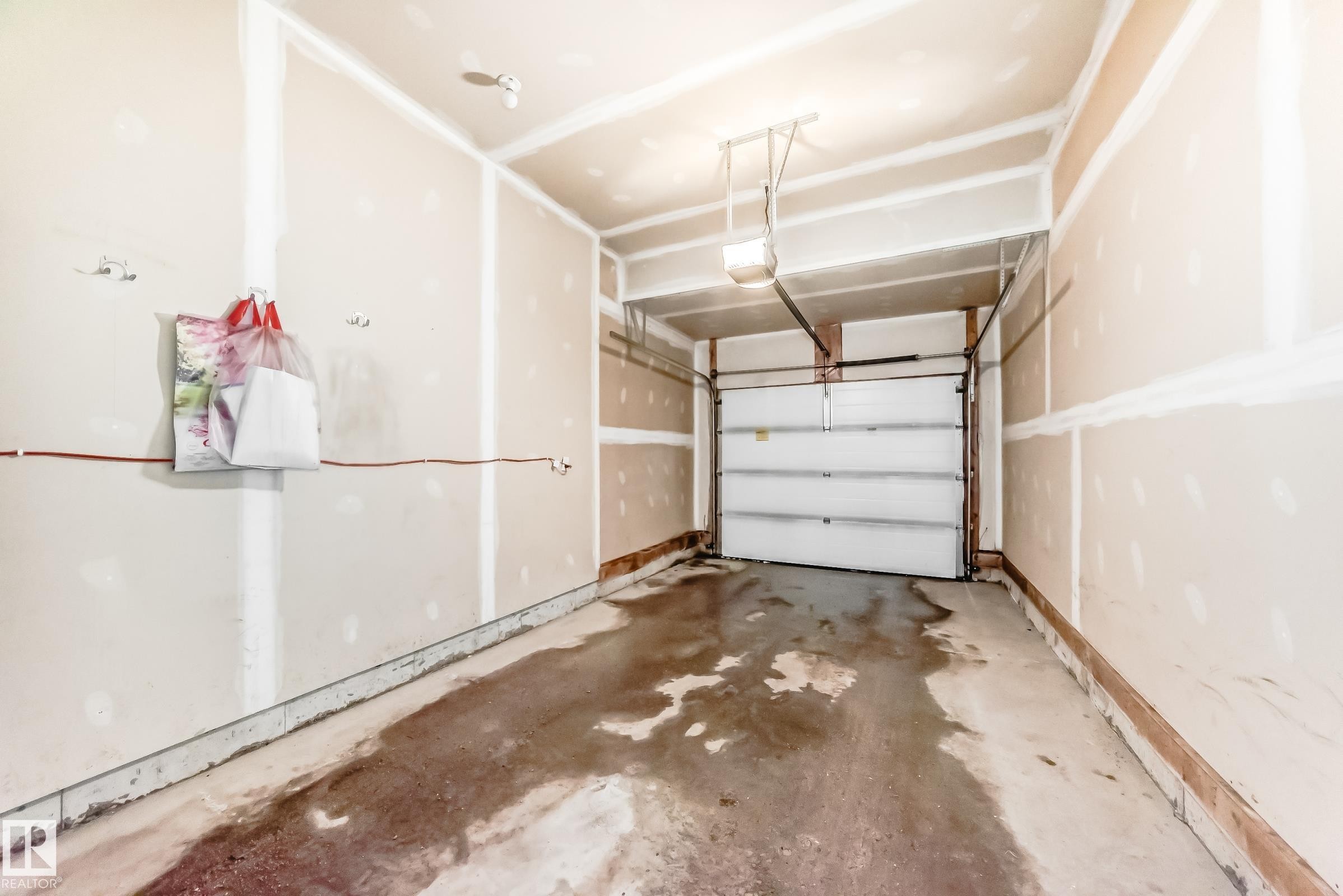 The property includes a garage with a roll-up door and a concrete floor - 8 13838 166Ave, Edmonton, AB - Indoor Photo Showing Garage