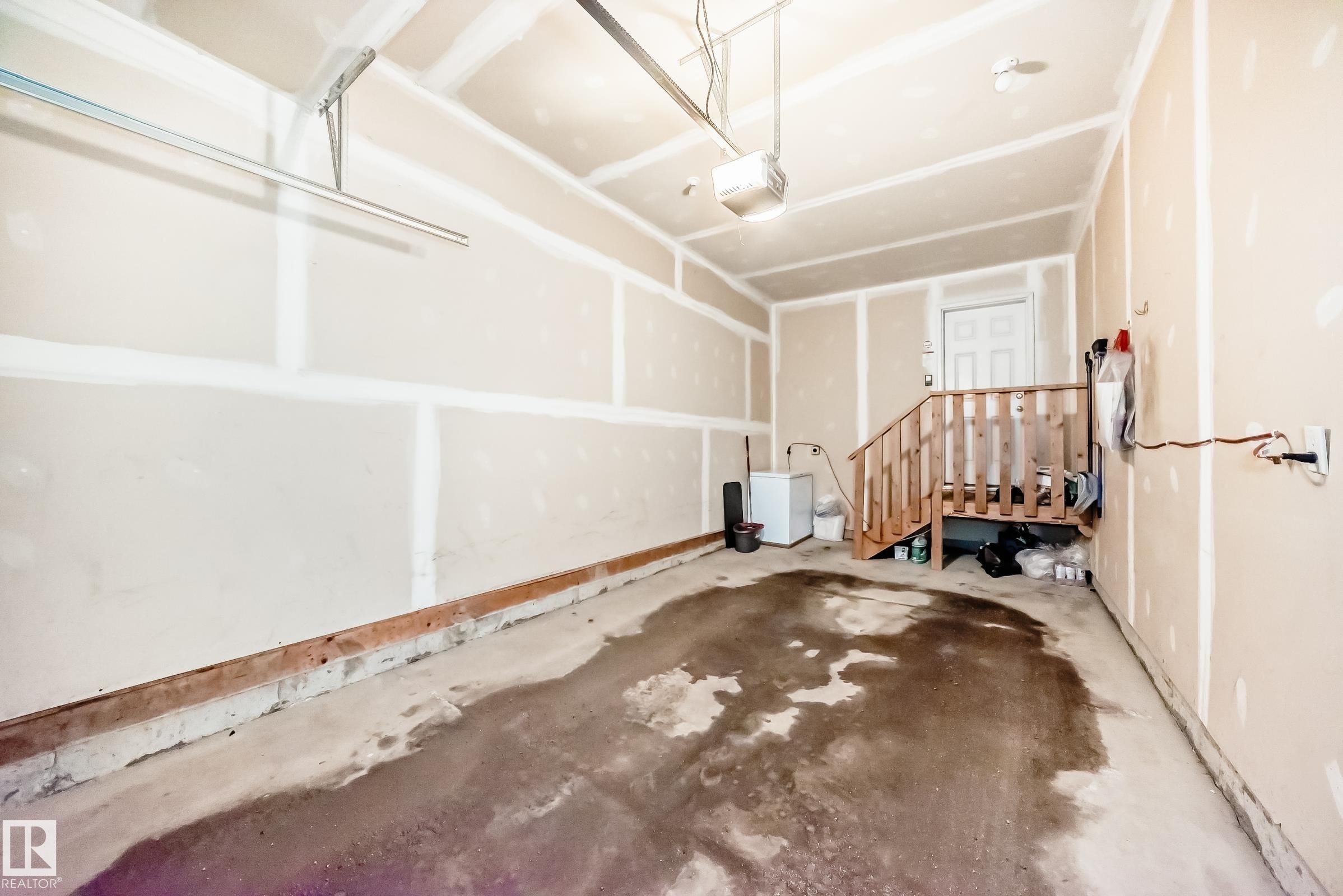 The property includes a spacious garage with a concrete floor and exposed drywall on the walls and ceiling - 8 13838 166Ave, Edmonton, AB - Indoor Photo Showing Garage