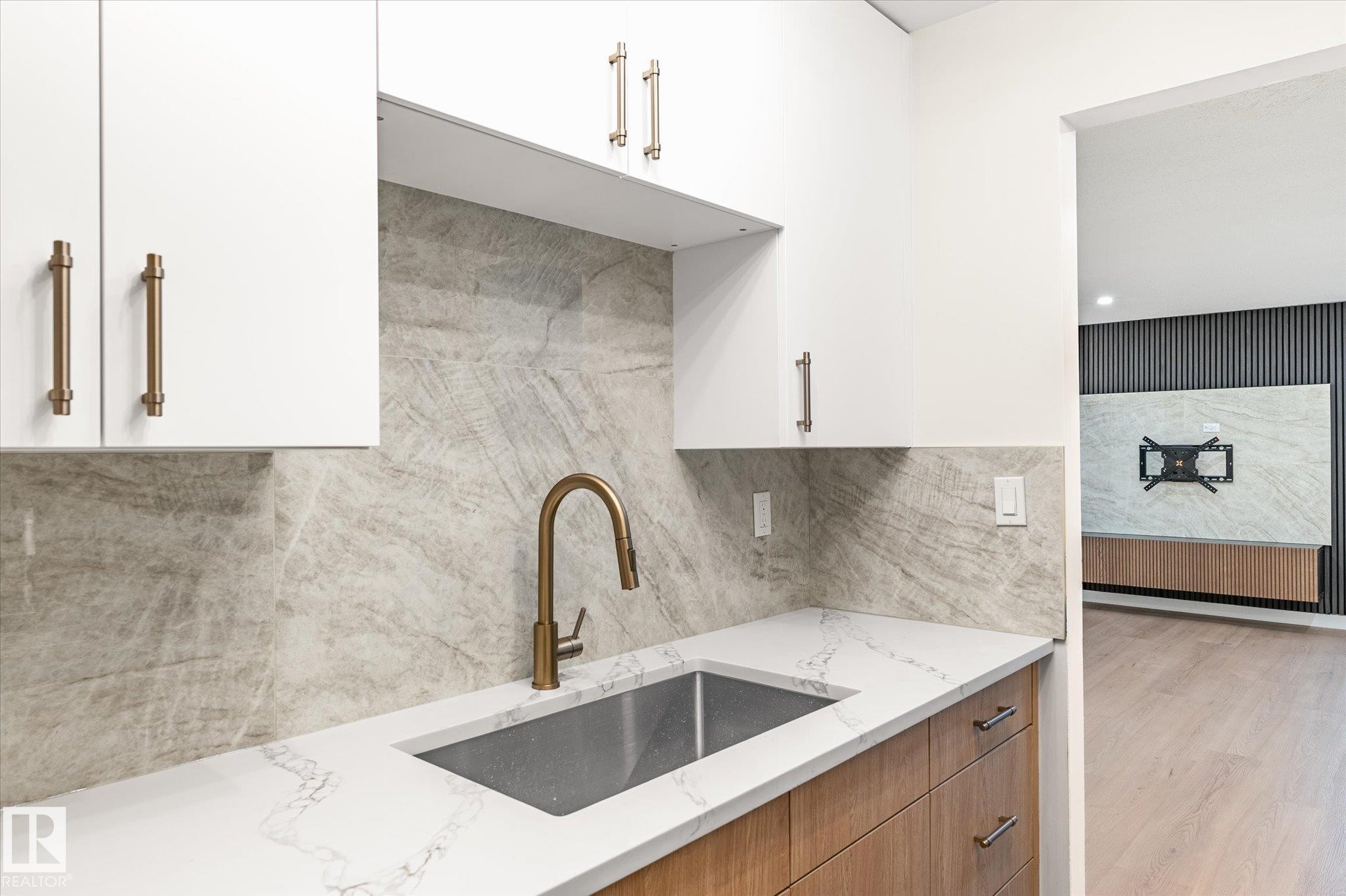 Kitchen featuring a white countertop with a double basin sink, a gold-toned faucet, and a stone backsplash - 6540 184 Street, Edmonton, AB - Indoor Photo Showing Kitchen