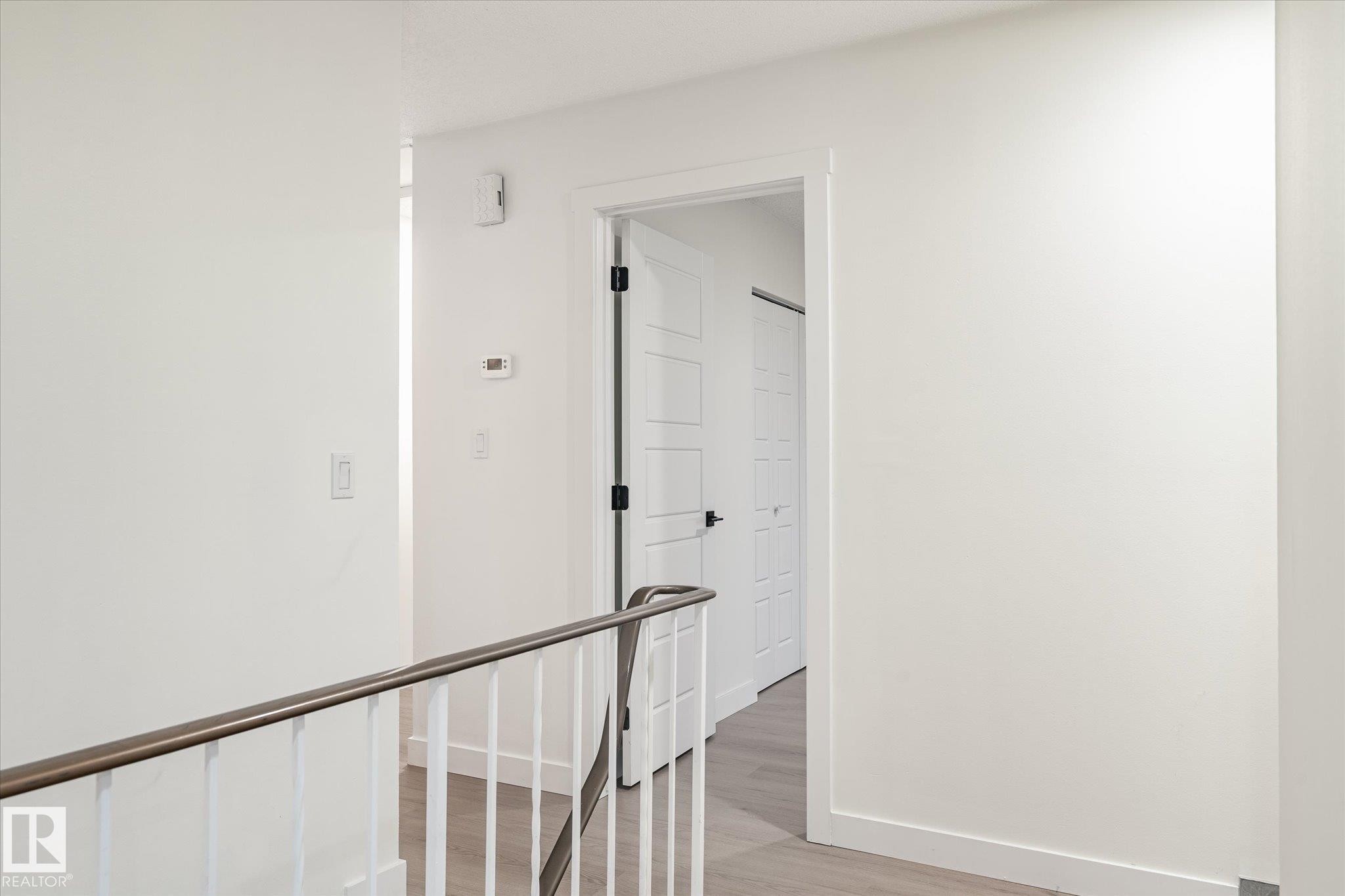 The property features a hallway with white walls, light-colored flooring, and a white railing with a dark top - 6540 184 Street, Edmonton, AB - Indoor Photo Showing Other Room