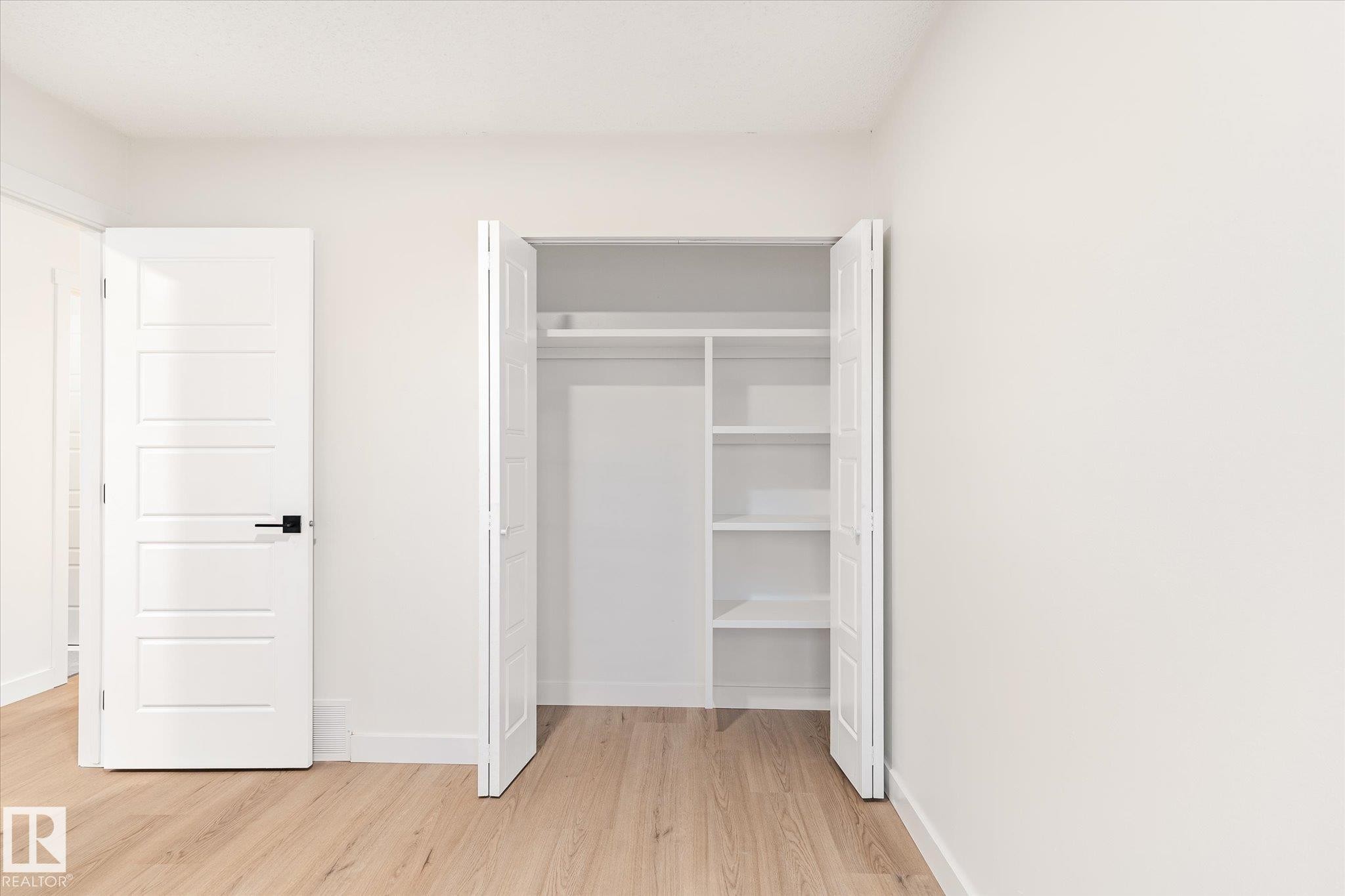 Room featuring light-toned flooring, white walls, and a closet with shelving and a hanging rod - 6540 184 Street, Edmonton, AB - Indoor