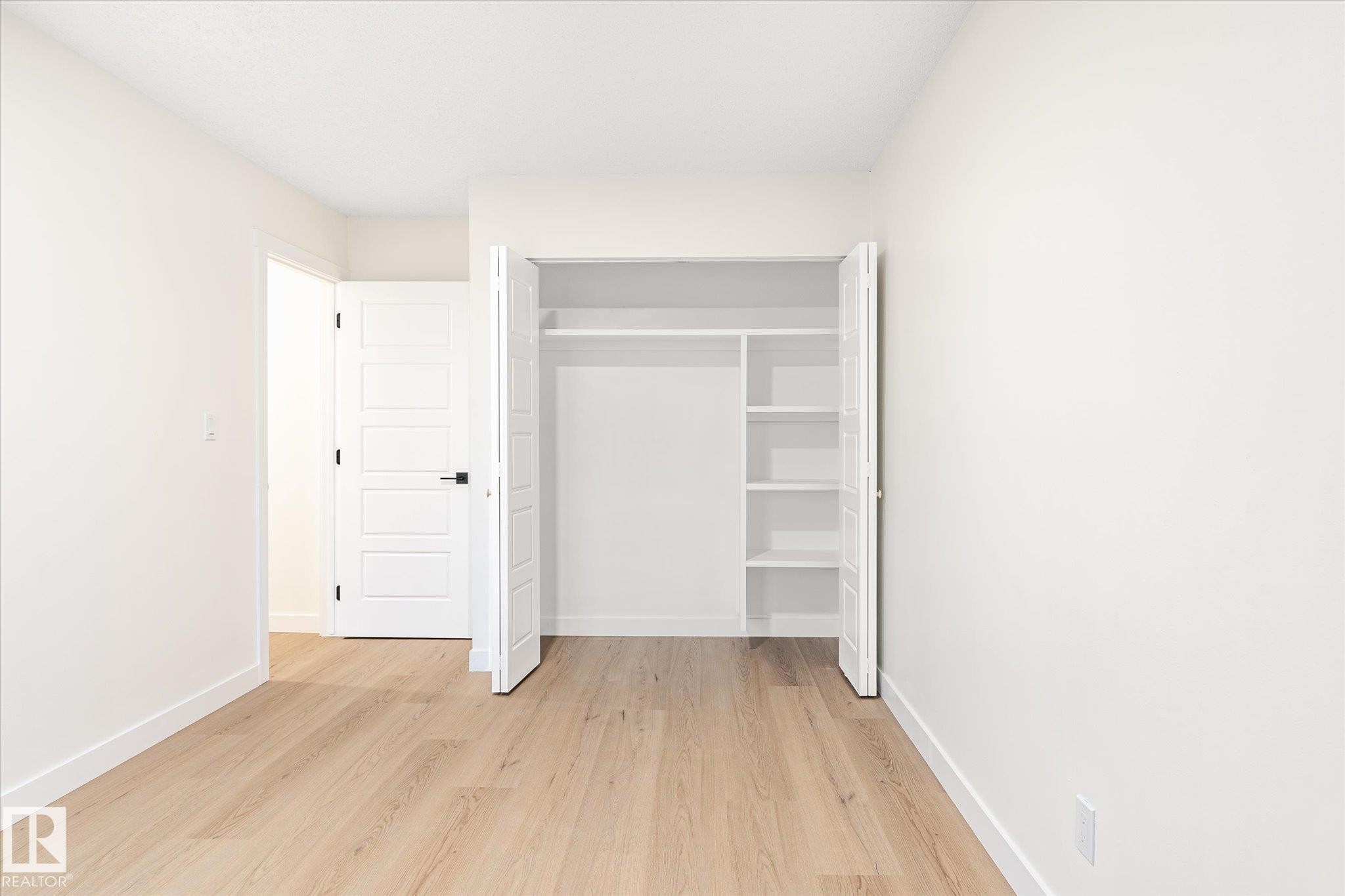 This room features light wood flooring, white walls, and a modern white door with a black handle - 6540 184 Street, Edmonton, AB - Indoor Photo Showing Other Room