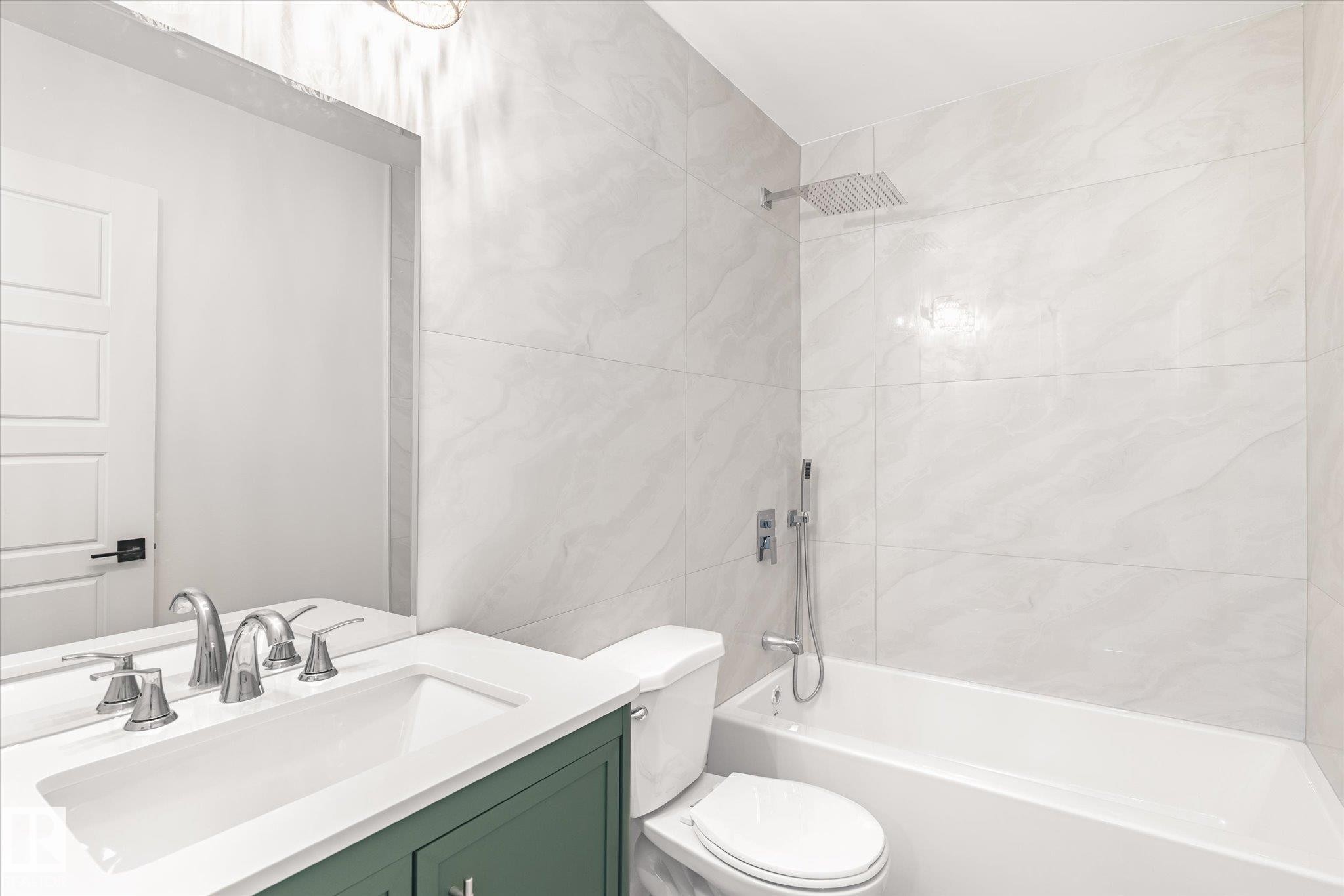 This bathroom features a vanity with a green cabinet, a white countertop, and a built-in sink with a chrome faucet - 6540 184 Street, Edmonton, AB - Indoor Photo Showing Bathroom