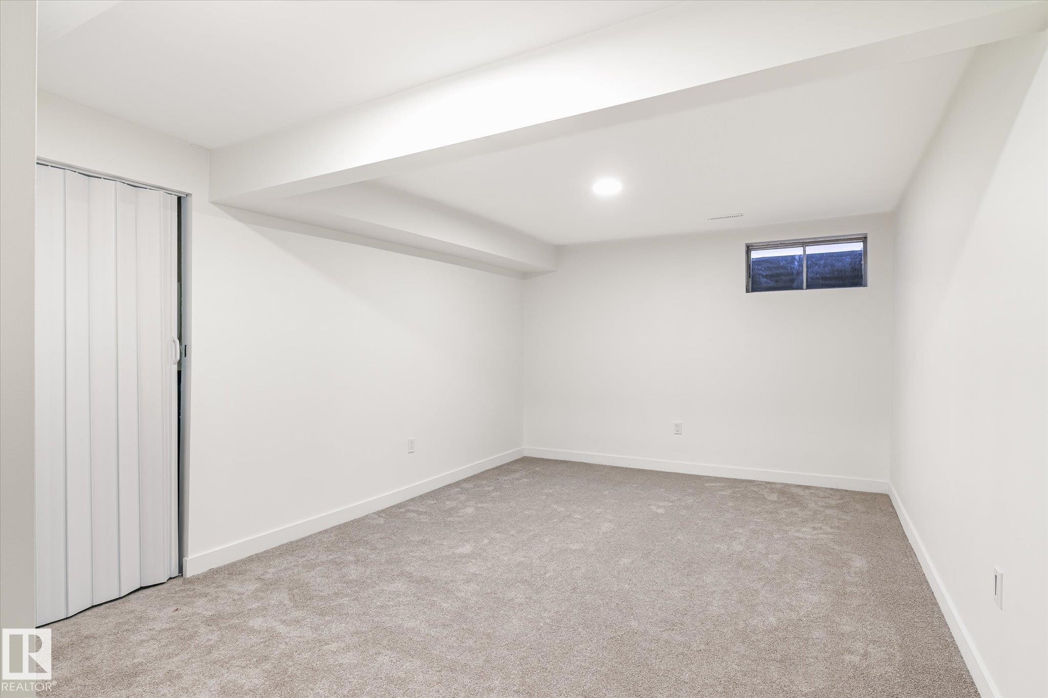 The room features carpeting, a window, and a white accordion-style door - 6540 184 Street, Edmonton, AB - Indoor Photo Showing Other Room