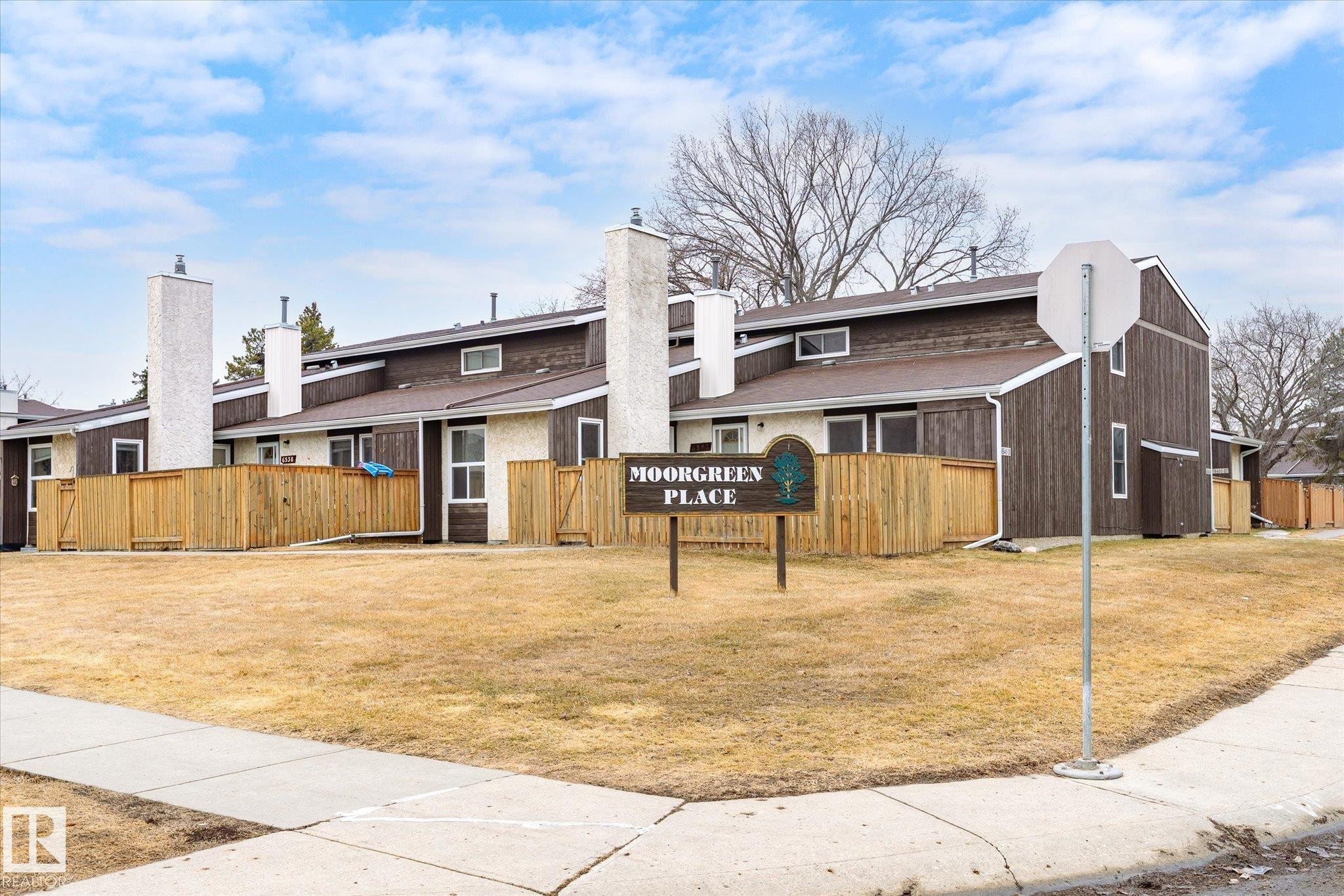 The property features a series of townhome-style residences with brown siding and white trim - 6540 184 Street, Edmonton, AB - Outdoor