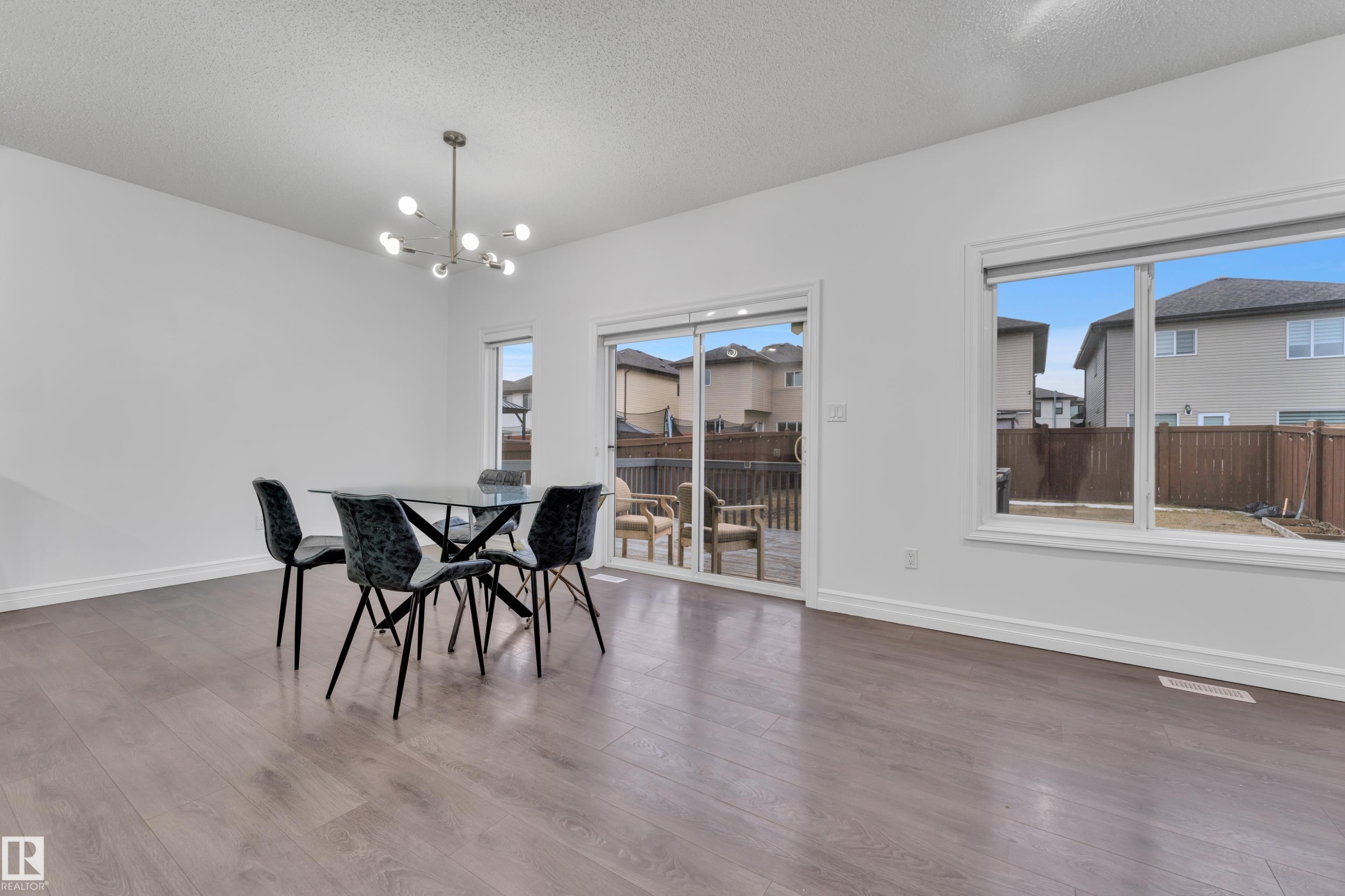 The property features an open living space with light wood flooring, large windows, and a sliding glass door providing natural light - 3235 13 Avenue, Edmonton, AB - Indoor