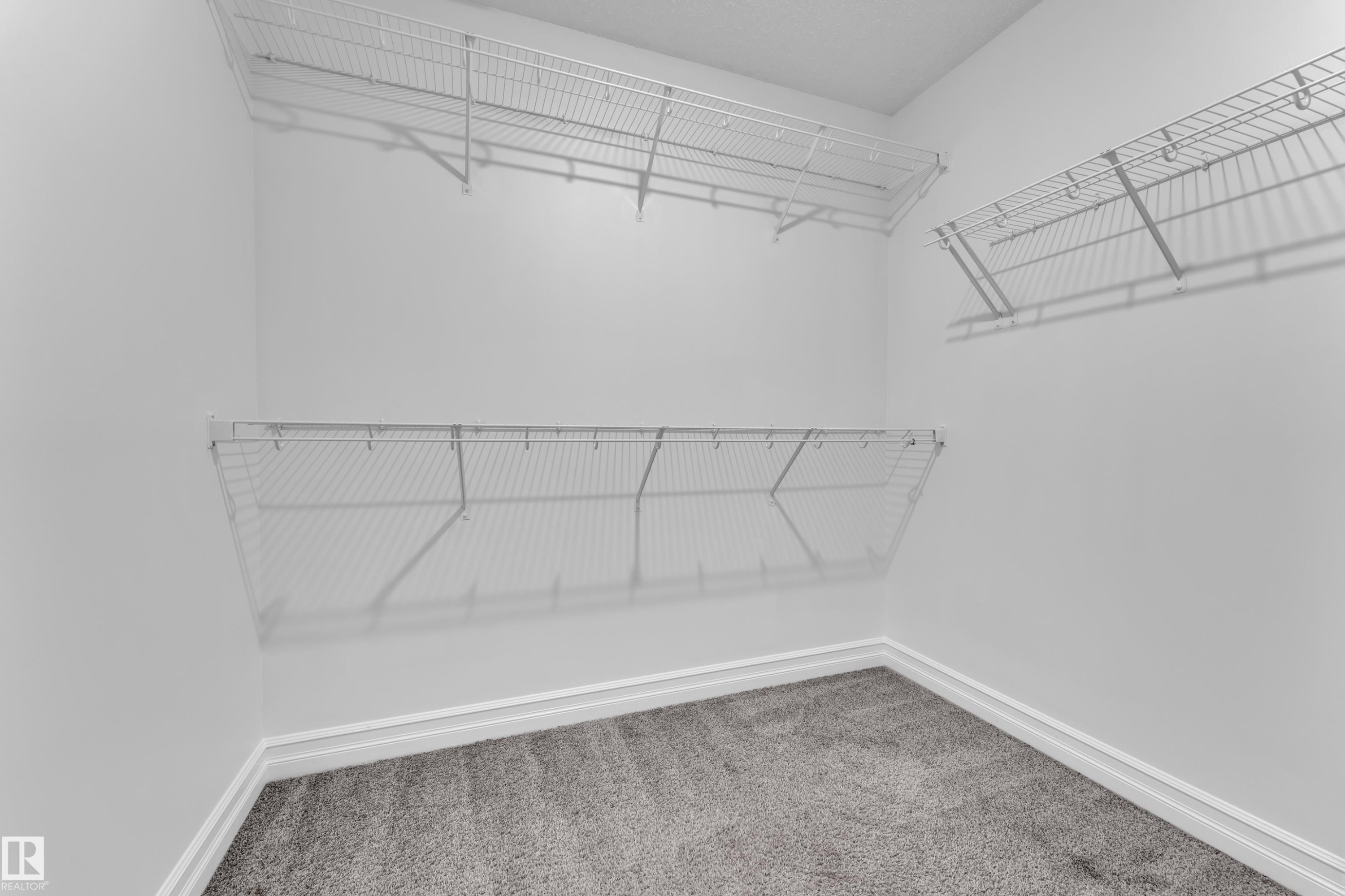 This closet features a neutral color palette, grey carpeting, and white wire shelving, offering practical storage solutions - 3235 13 Avenue, Edmonton, AB - Indoor With Storage