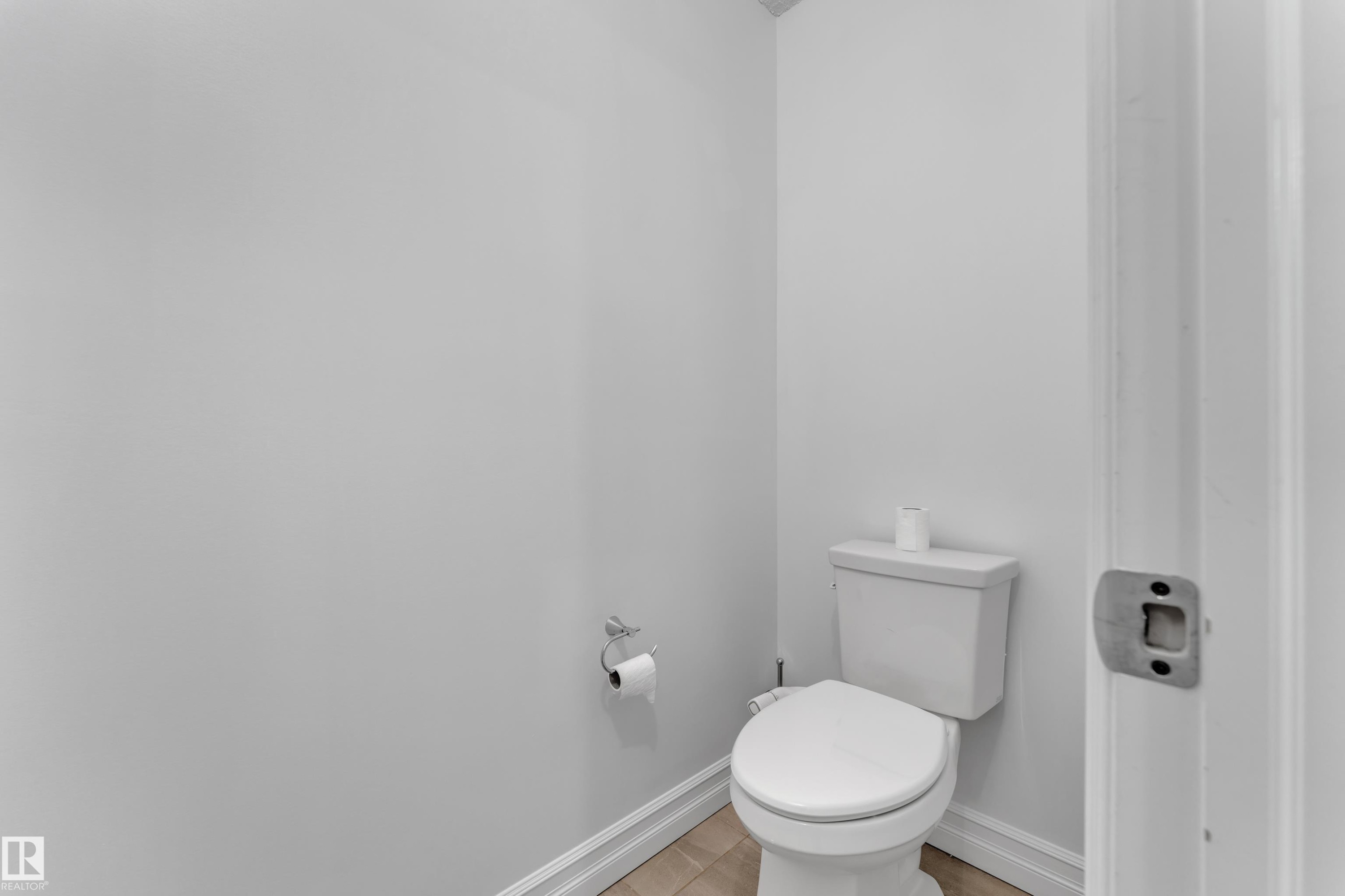 This bathroom features a white toilet, light-colored walls, and a toilet paper holder - 3235 13 Avenue, Edmonton, AB - Indoor Photo Showing Bathroom