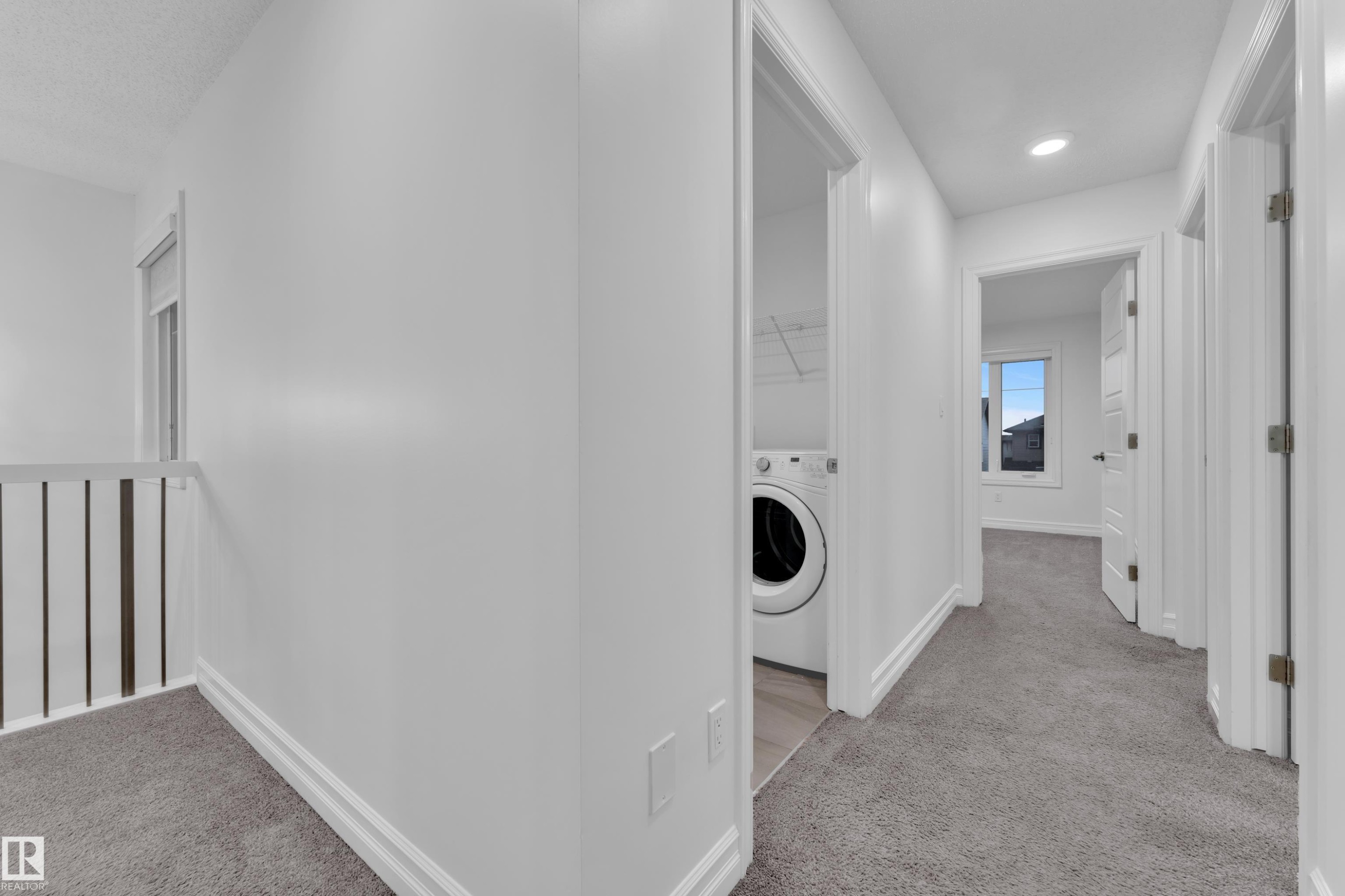 This property features a dedicated laundry area with a washing machine, carpeting throughout the hall, and a window providing natural light - 3235 13 Avenue, Edmonton, AB - Indoor Photo Showing Laundry Room