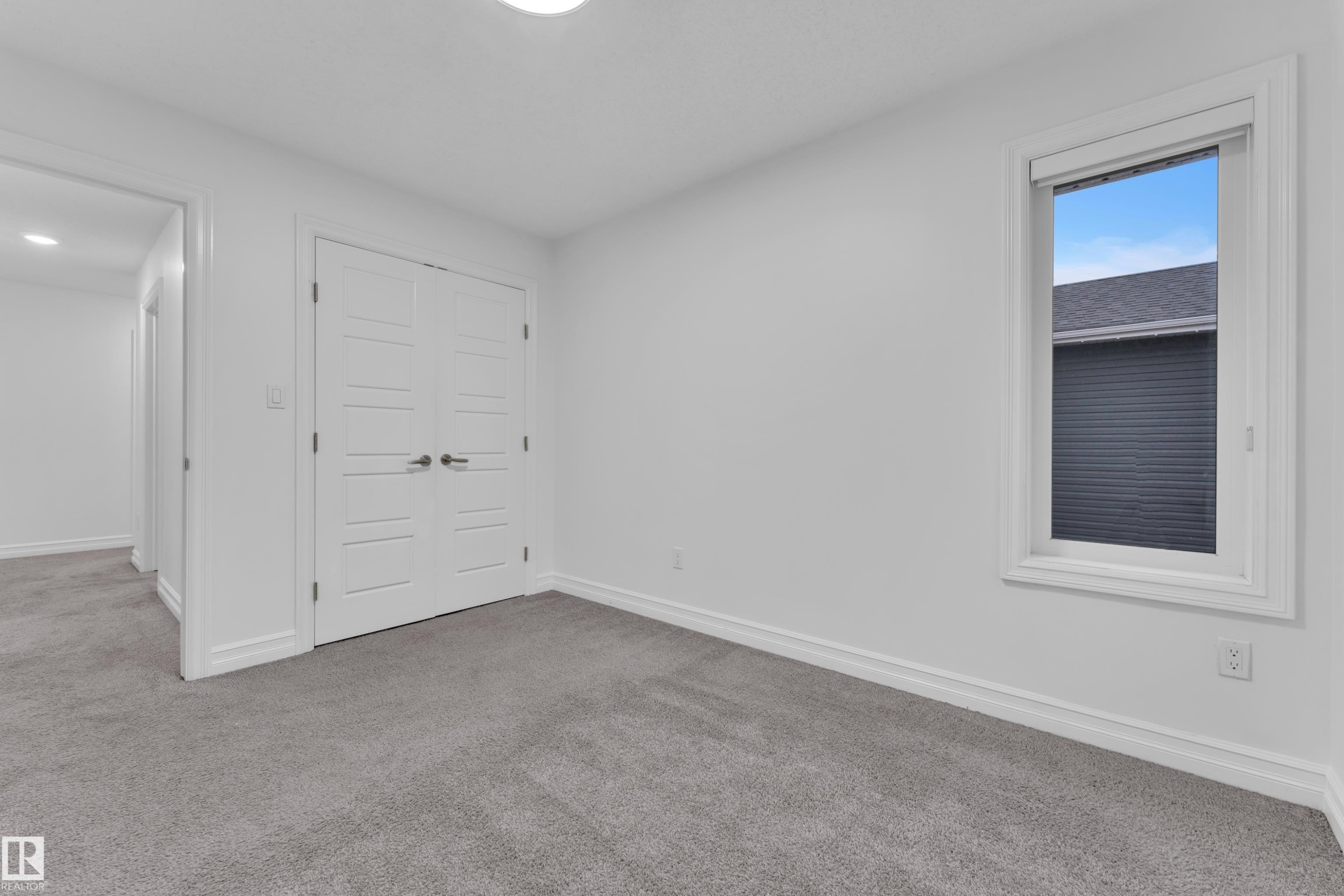 This room features light gray carpeting, white walls, and a window with a view of a nearby roofline - 3235 13 Avenue, Edmonton, AB - Indoor Photo Showing Other Room