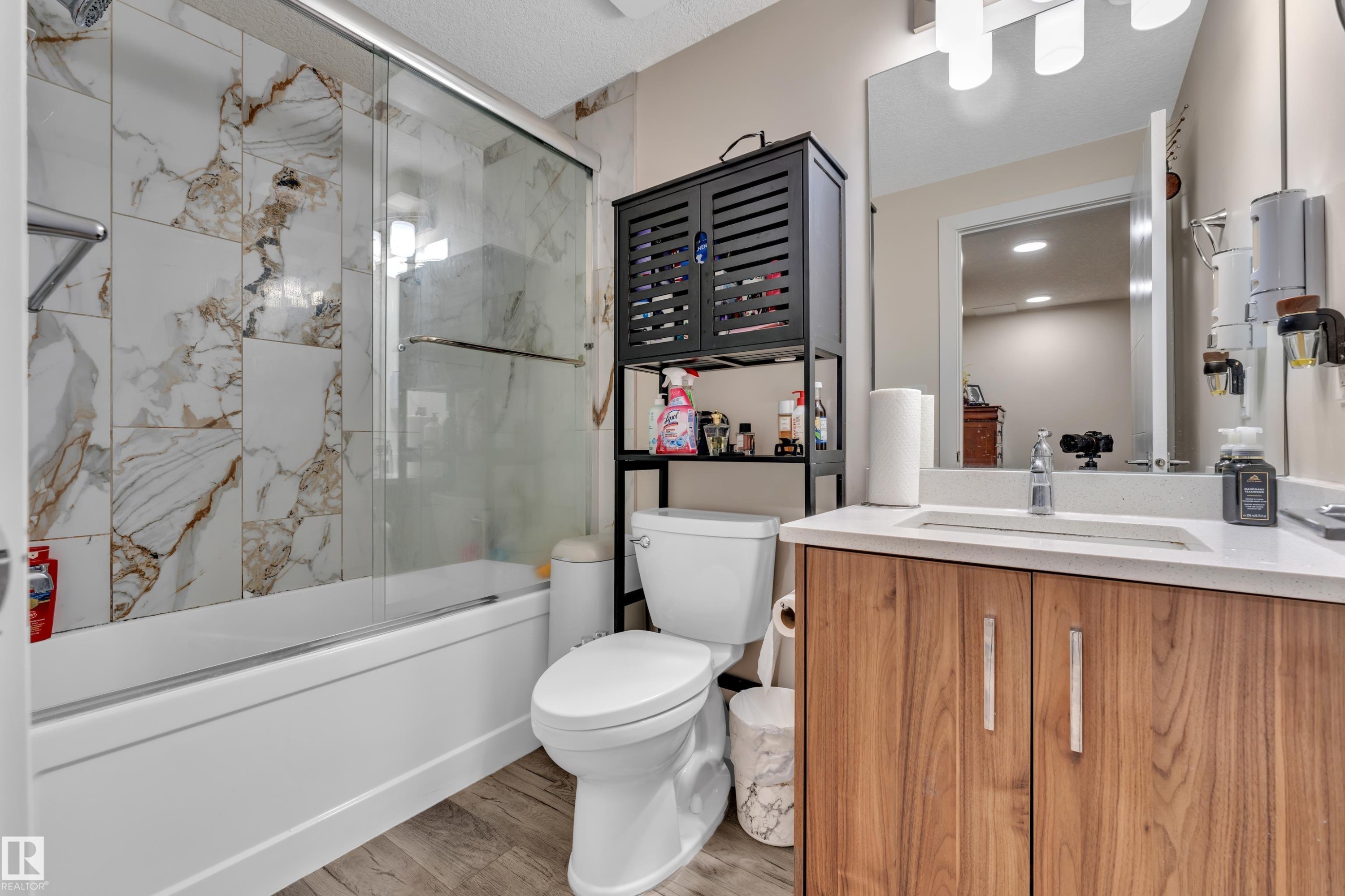 The bathroom features a bathtub with a glass sliding shower door and marble-patterned wall tiles - 3235 13 Avenue, Edmonton, AB - Indoor Photo Showing Bathroom