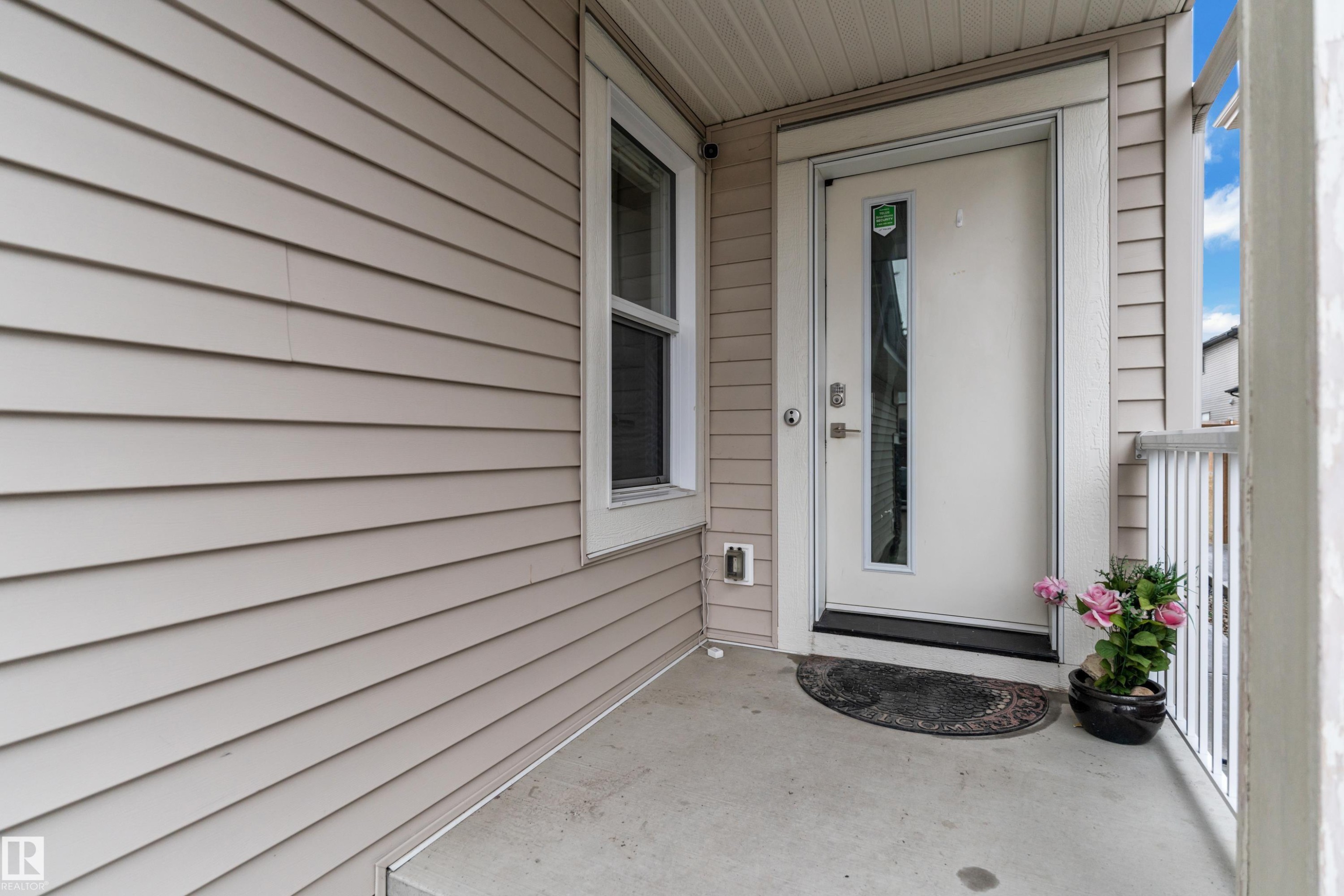 The property features a front entrance with a white door and a narrow vertical window, set on a concrete porch - 3235 13 Avenue, Edmonton, AB - Outdoor With Exterior