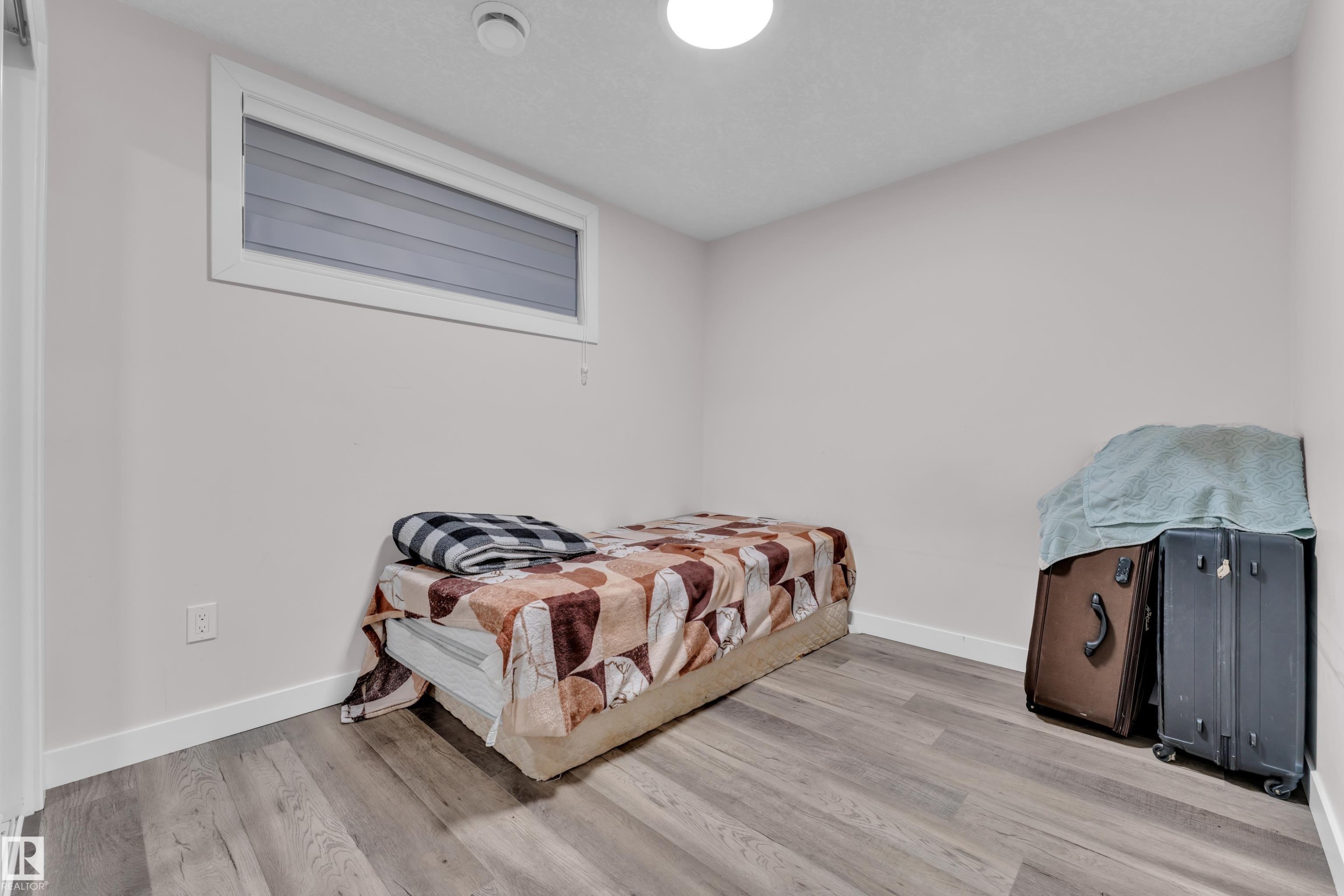 The room features light gray walls, a window with horizontal blinds, and wide plank flooring - 3235 13 Avenue, Edmonton, AB - Indoor Photo Showing Bedroom
