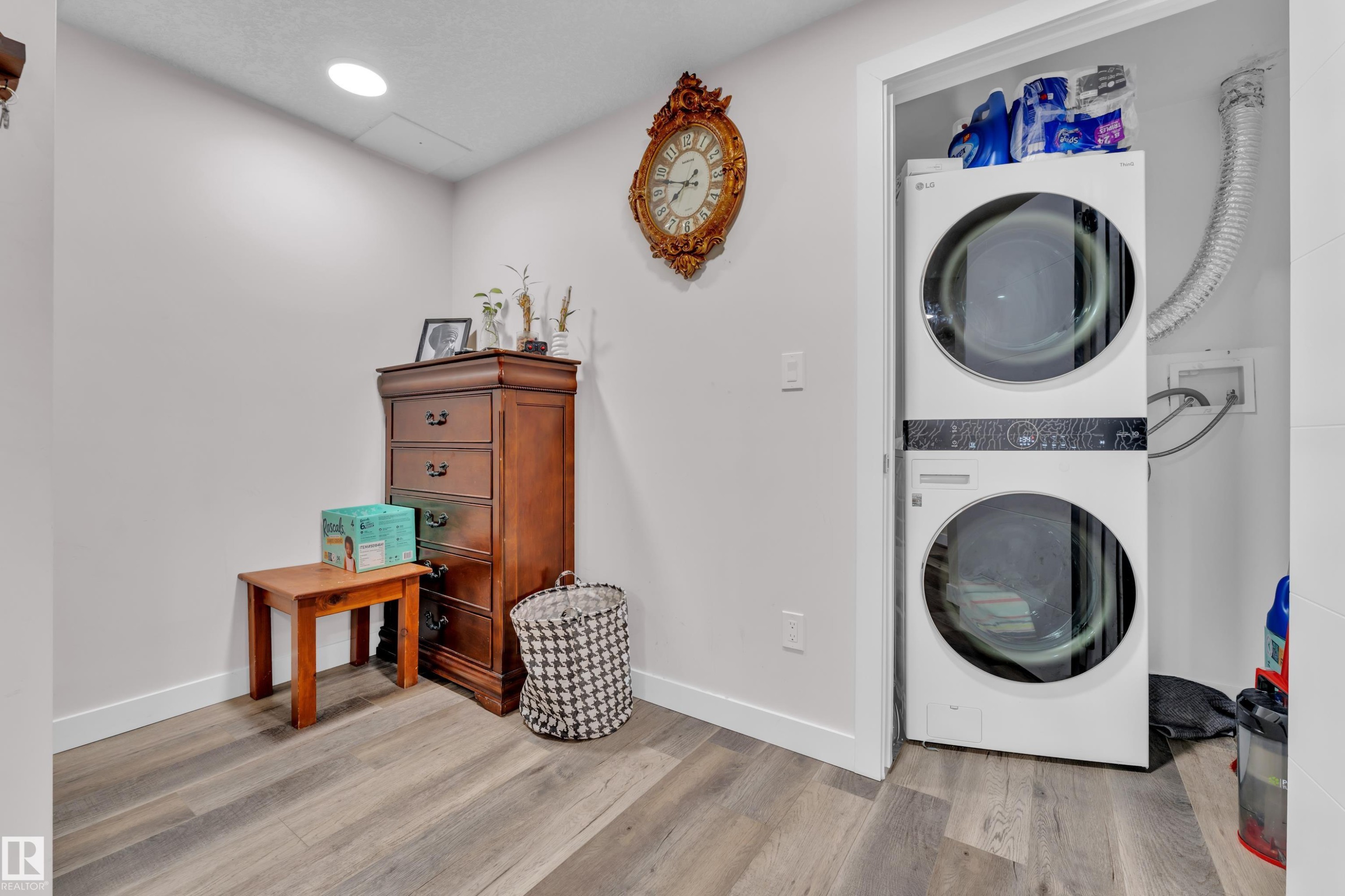 The property features a laundry area with a stackable washer and dryer unit, and wood-look flooring - 3235 13 Avenue, Edmonton, AB - Indoor Photo Showing Laundry Room