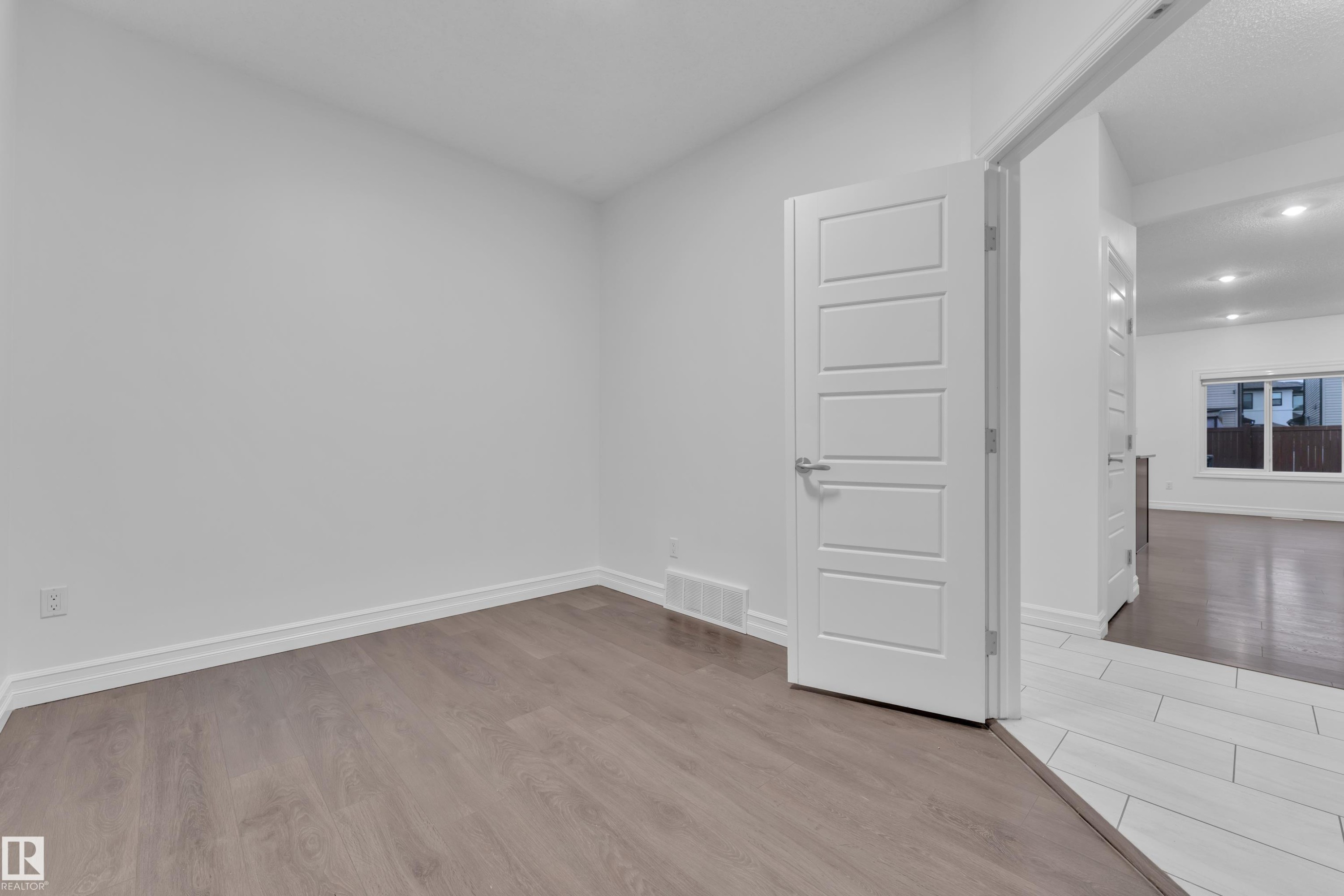 This versatile room features light-toned flooring, white baseboards, and a modern door with a satin nickel handle - 3235 13 Avenue, Edmonton, AB - Indoor Photo Showing Other Room