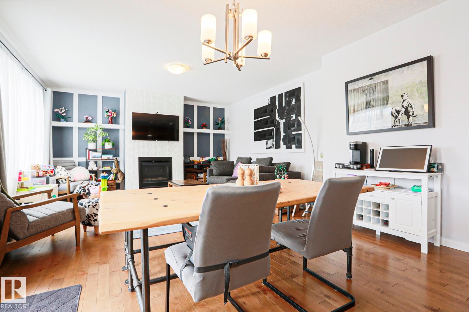 The living area features hardwood floors, a fireplace, and built-in shelving with accent lighting - 18 Enchanted Way, St. Albert, AB