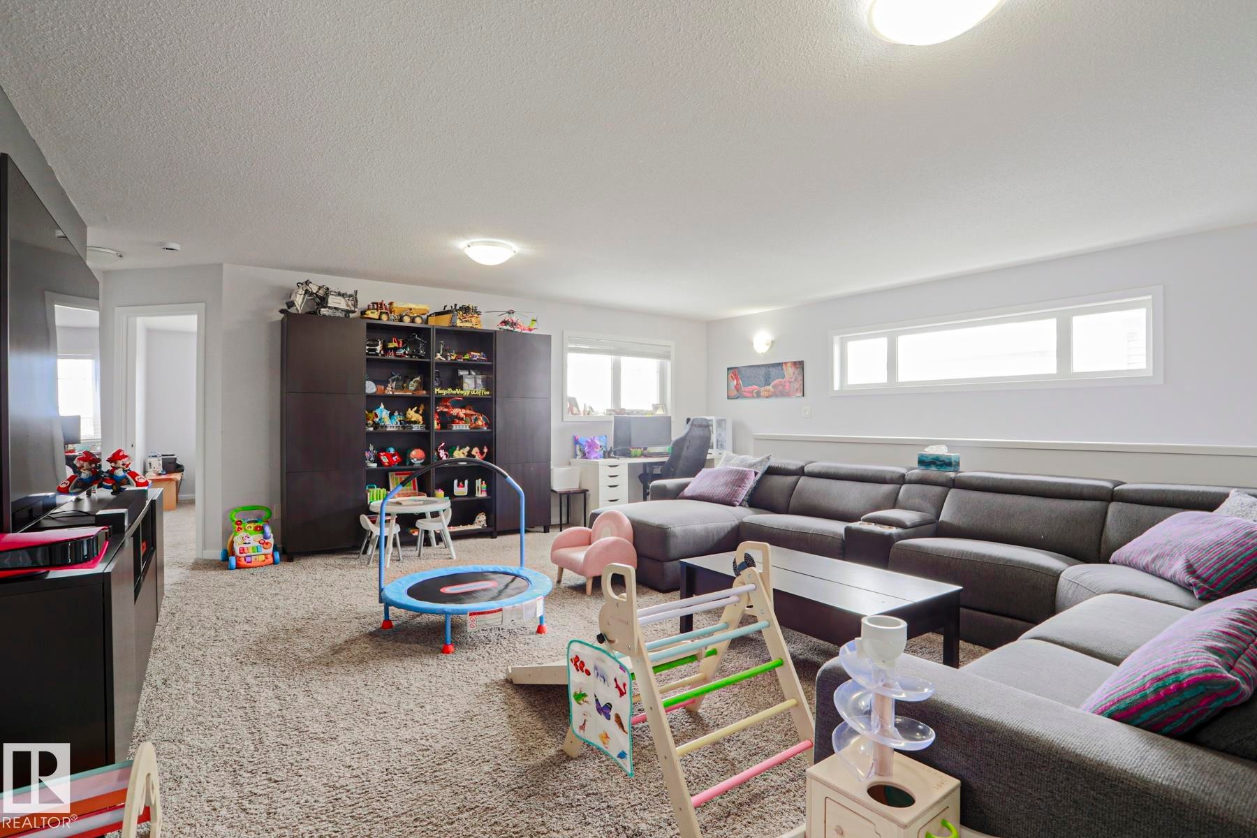 This spacious room features neutral-toned carpet flooring, recessed lighting, and white walls - 18 Enchanted Way, St. Albert, AB