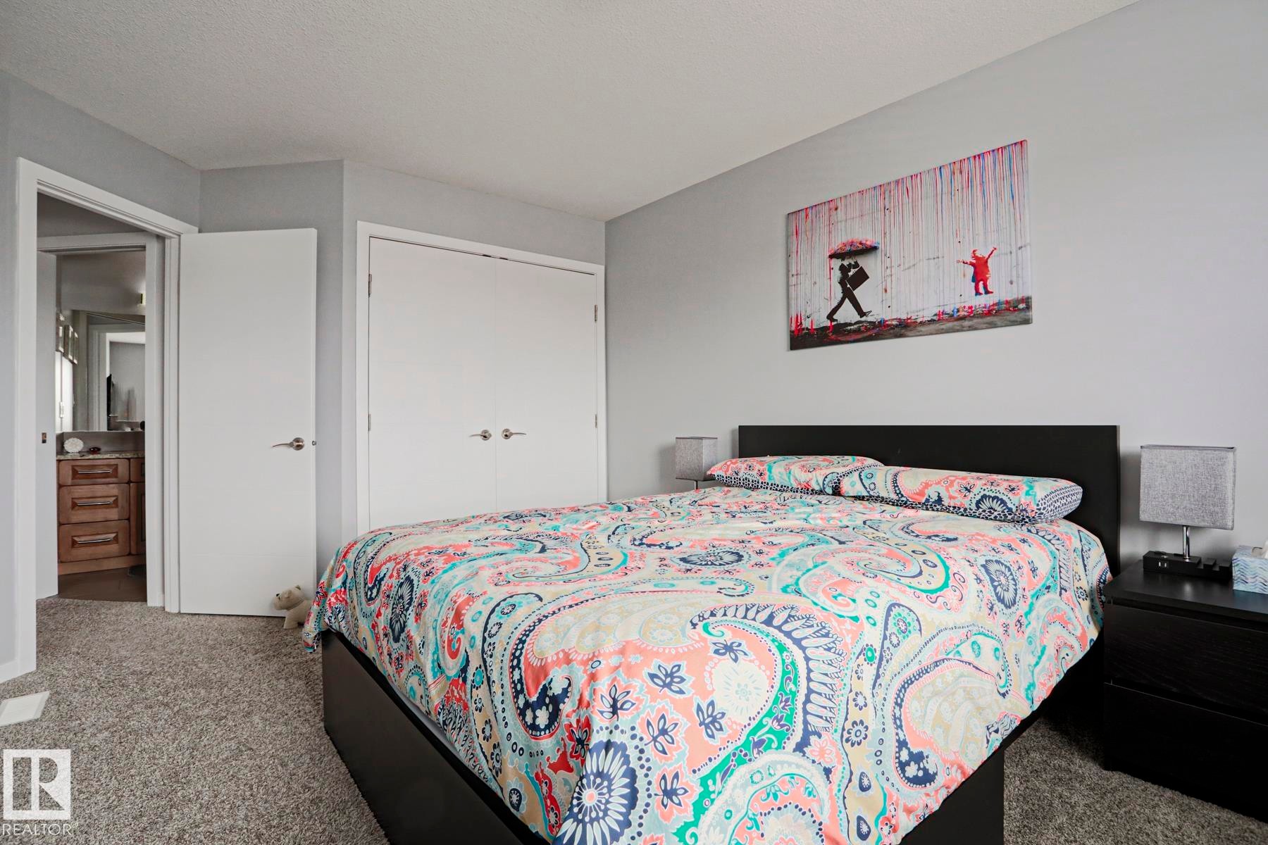 This bedroom features plush grey carpeting, light grey walls, and a convenient closet with white double doors - 18 Enchanted Way, St. Albert, AB