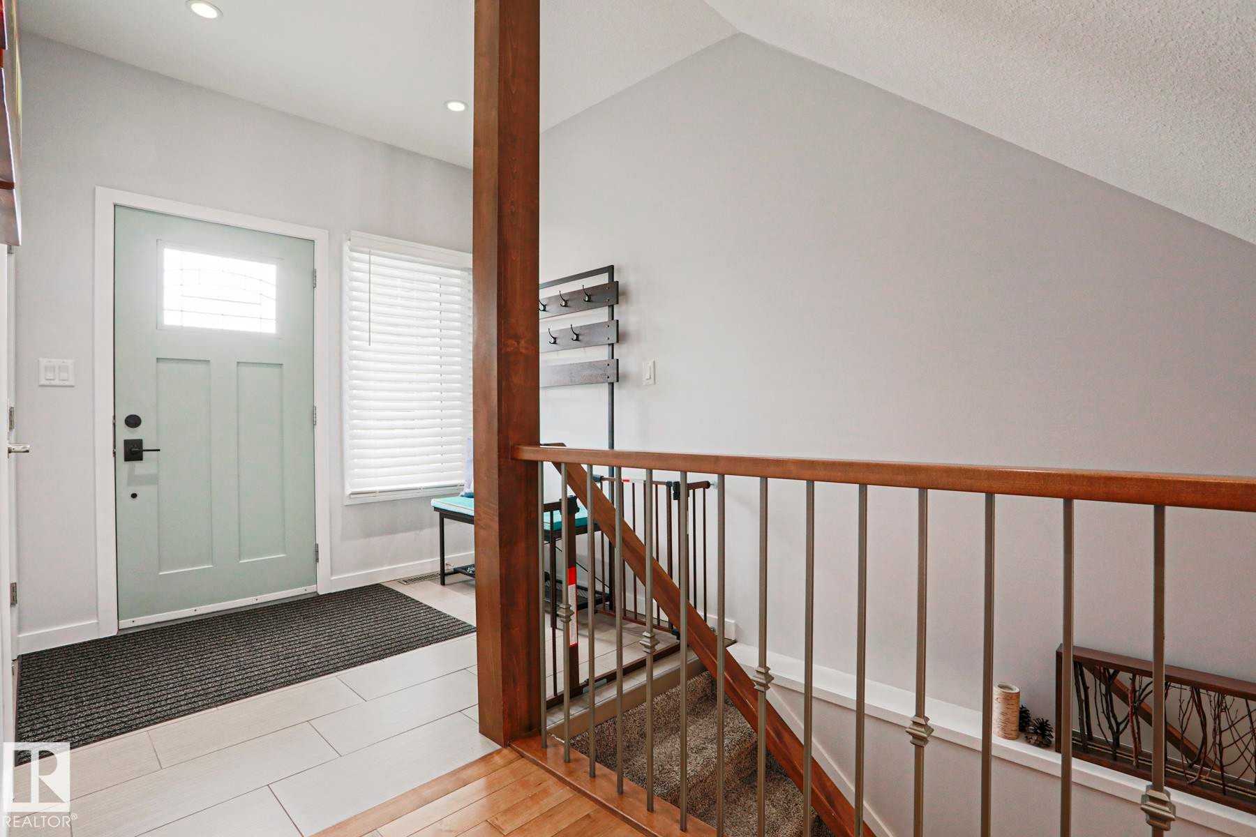 The entryway features a light-colored door with a window, tile flooring, and recessed lighting - 18 Enchanted Way, St. Albert, AB