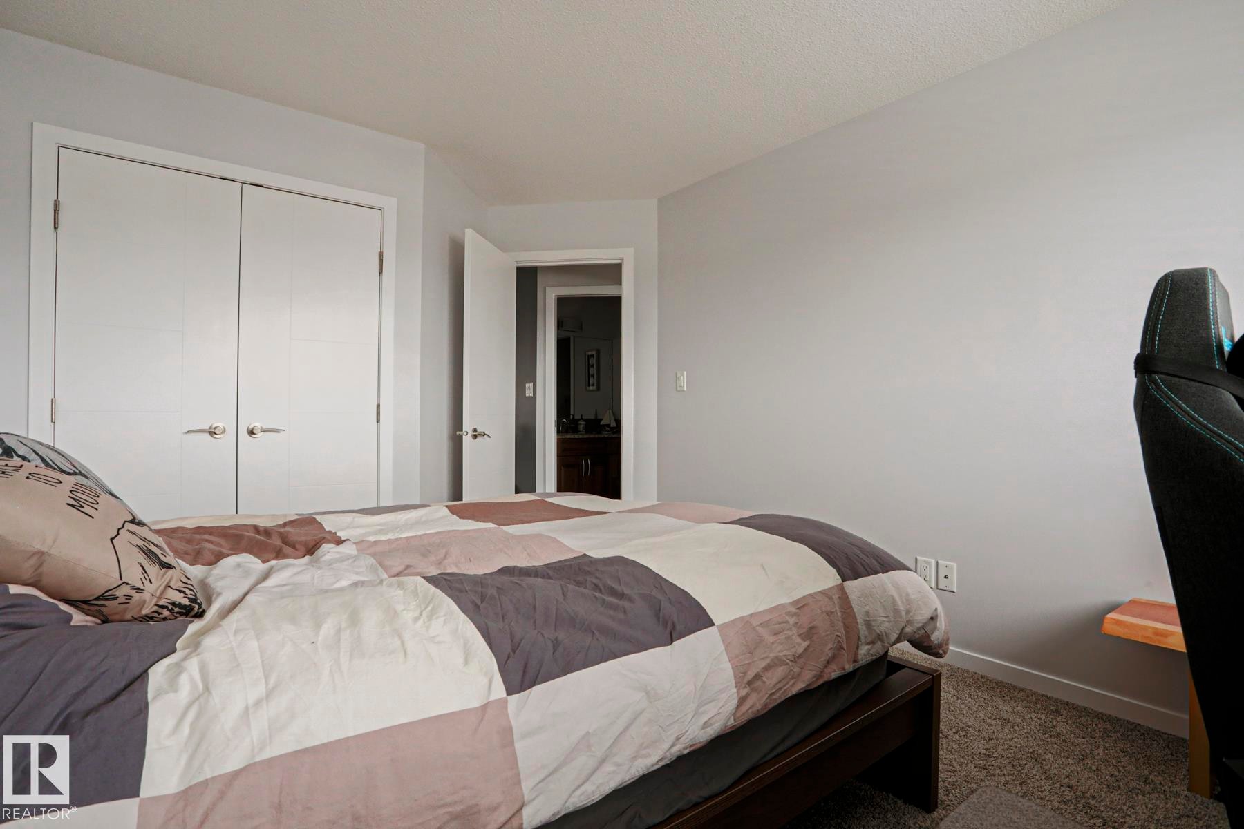 The bedroom features light gray walls, carpeted flooring, and a closet with double doors - 18 Enchanted Way, St. Albert, AB