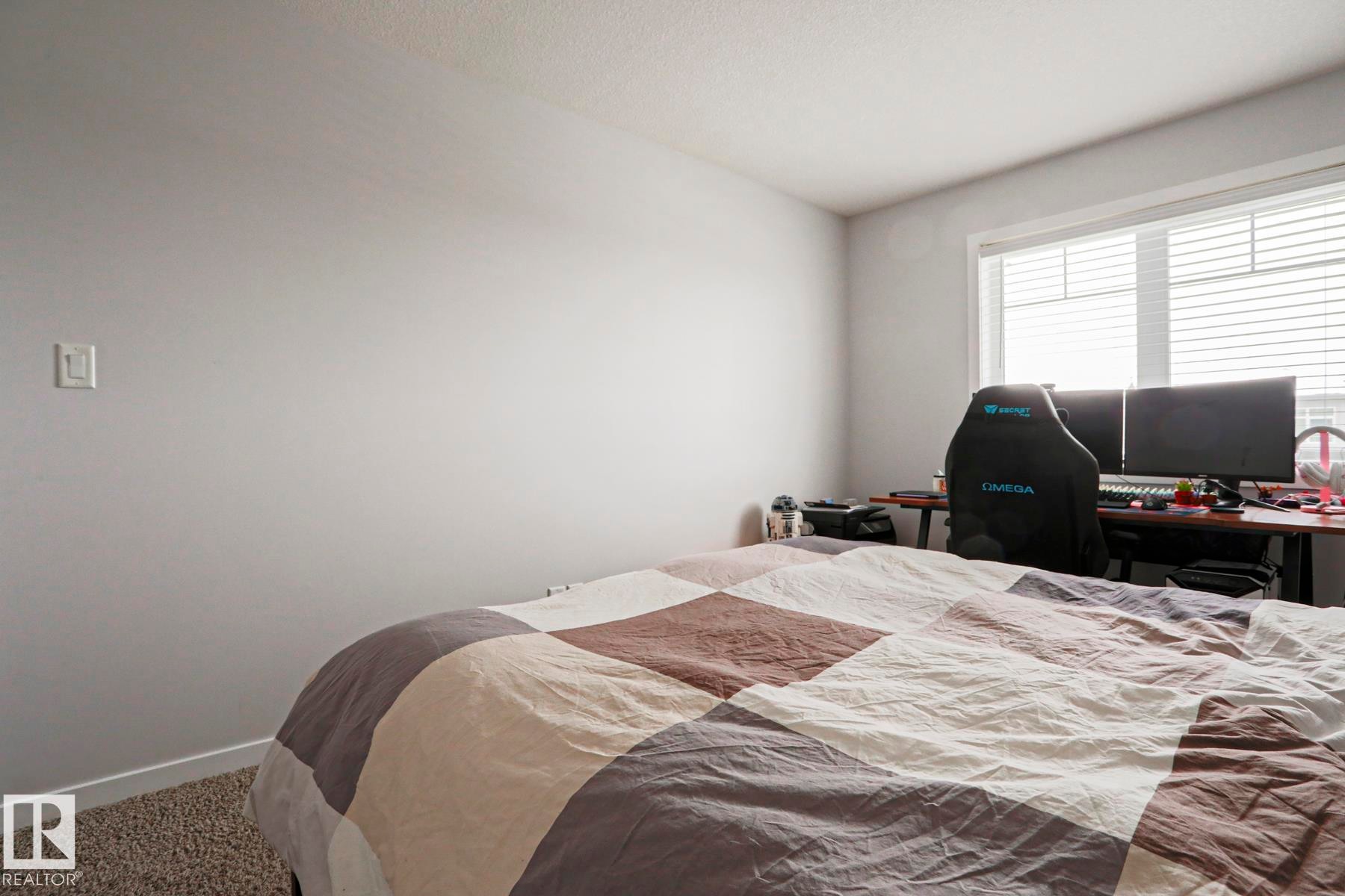 This room features light gray walls, a window with horizontal blinds, and a textured carpet - 18 Enchanted Way, St. Albert, AB