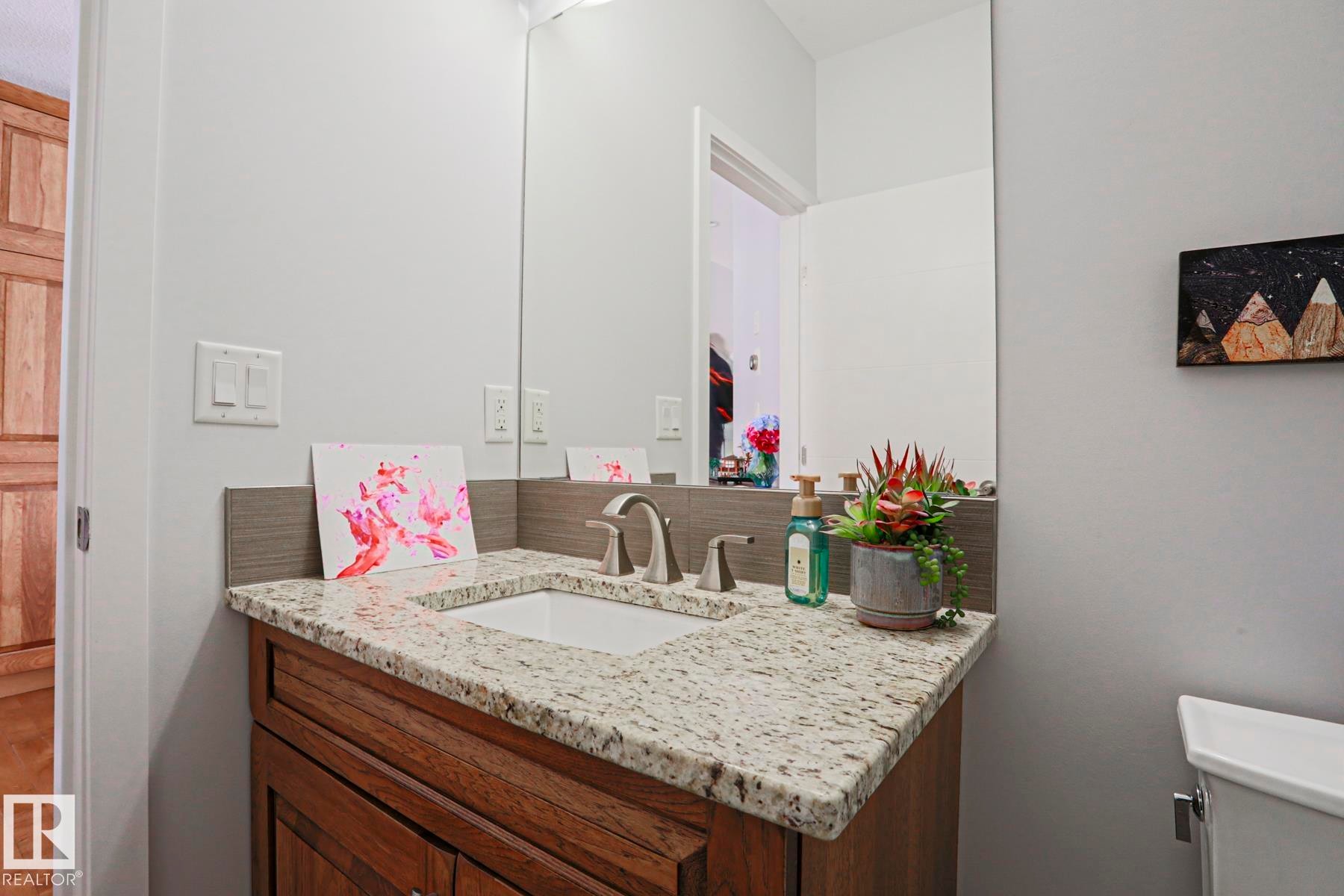 The bathroom features a vanity with a granite countertop, an undermount sink, and a wood cabinet - 18 Enchanted Way, St. Albert, AB
