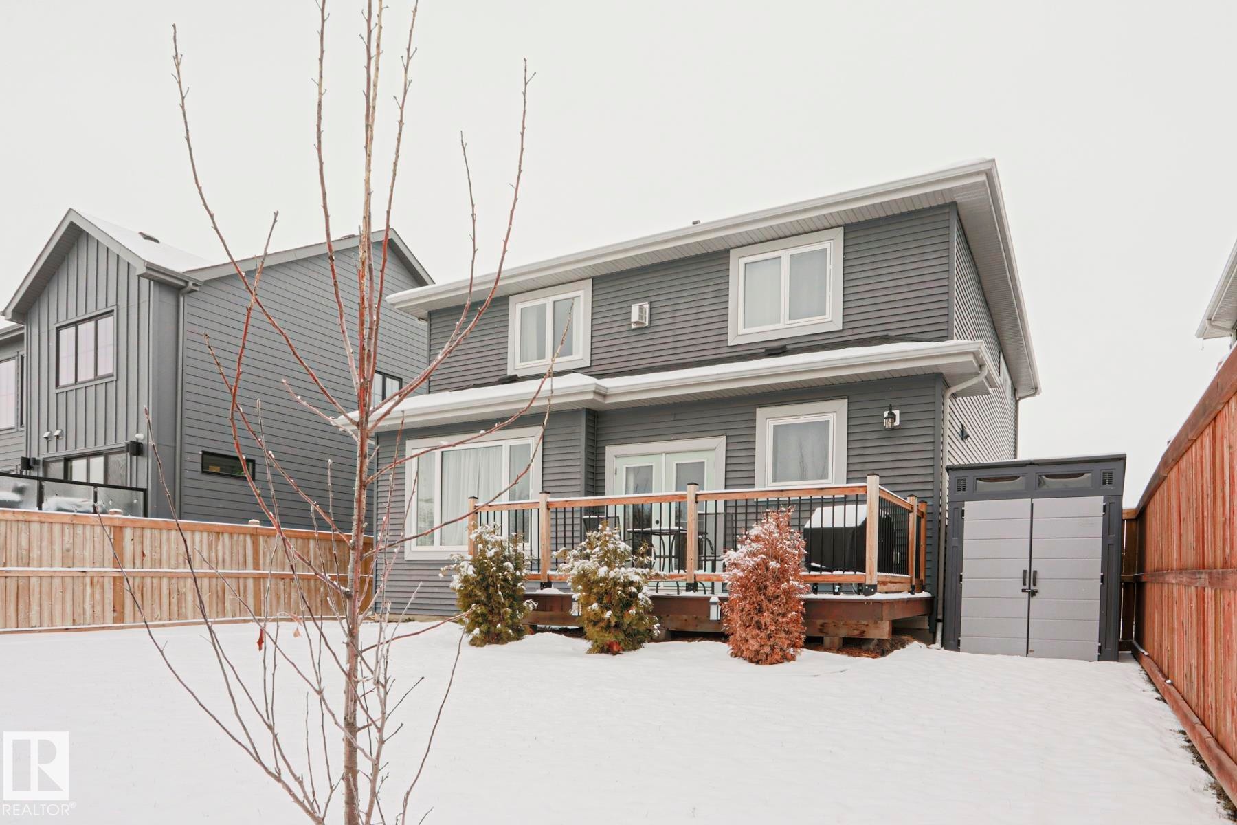 The property features a two-story exterior with horizontal siding, multiple windows, and a wooden deck - 18 Enchanted Way, St. Albert, AB