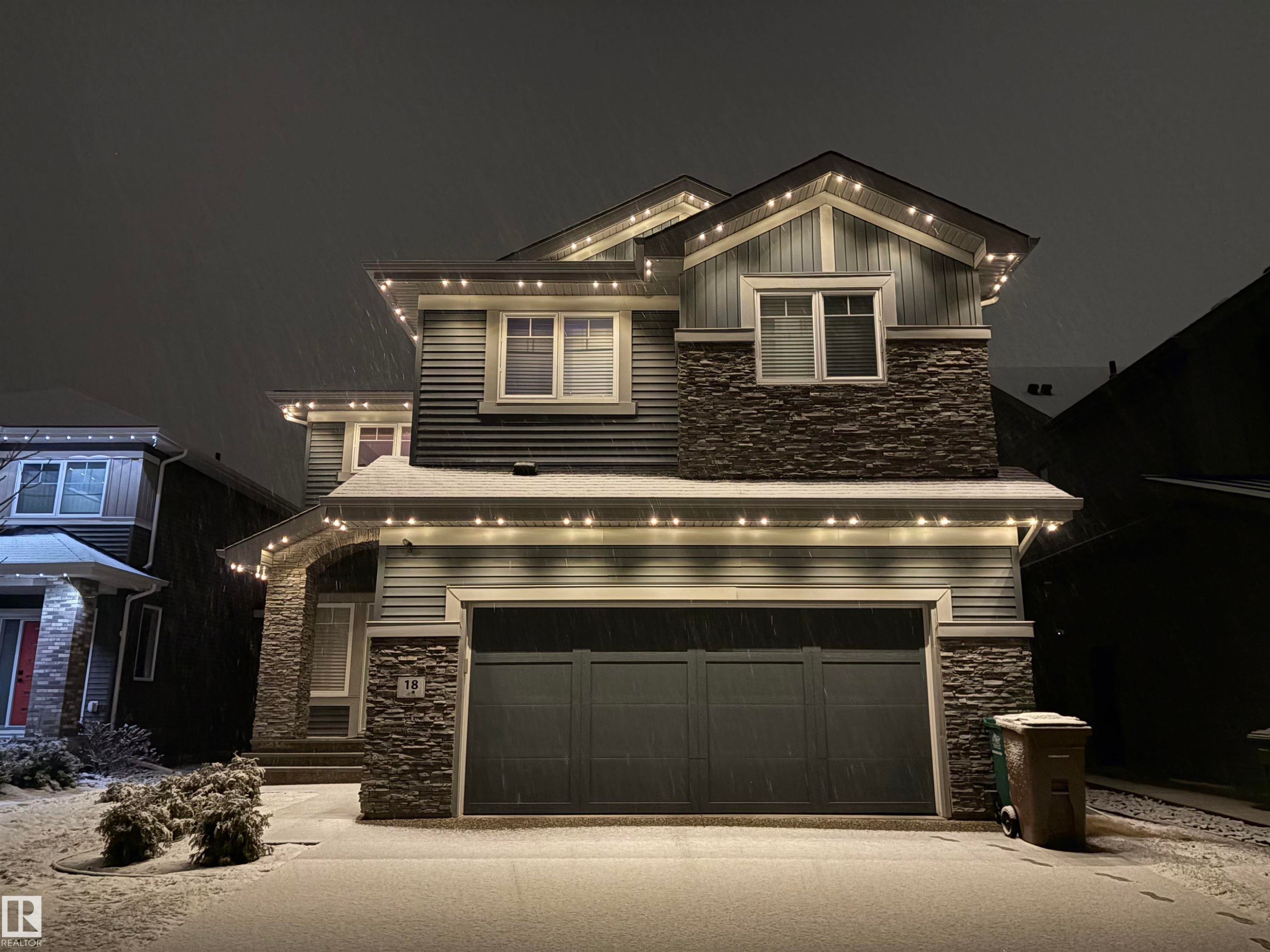 The property features a two-story exterior with horizontal siding and stone accents, a prominent front-facing garage, and a covered entry - 18 Enchanted Way, St. Albert, AB