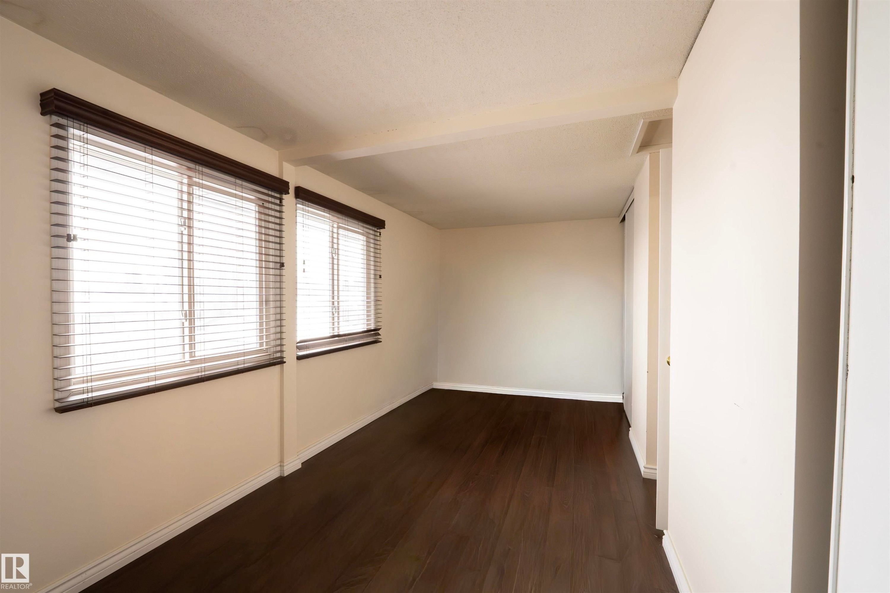 This room features dark wood flooring, light-colored walls, and two windows with blinds - 1728 37 Street, Edmonton, AB - Indoor Photo Showing Other Room