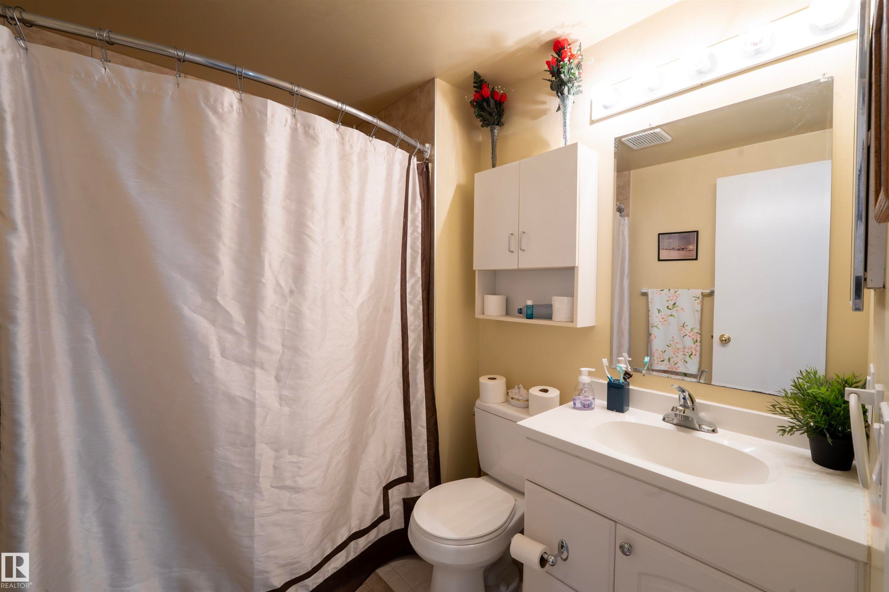The bathroom features a white vanity with a single basin sink and a mirror with overhead lighting - 1728 37 Street, Edmonton, AB - Indoor Photo Showing Bathroom