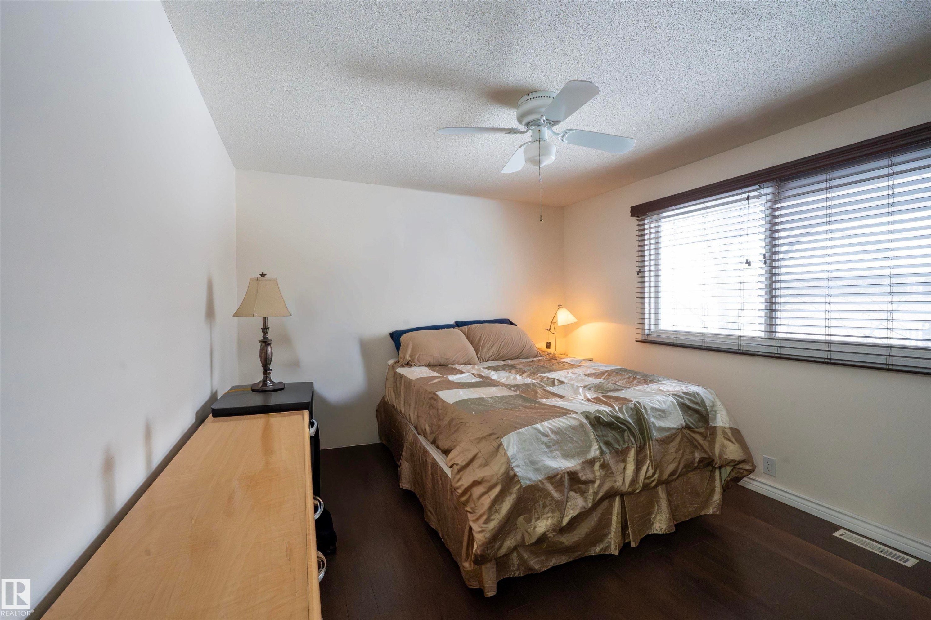 This room features dark wood flooring, a window with horizontal blinds, and a ceiling fan - 1728 37 Street, Edmonton, AB - Indoor Photo Showing Bedroom