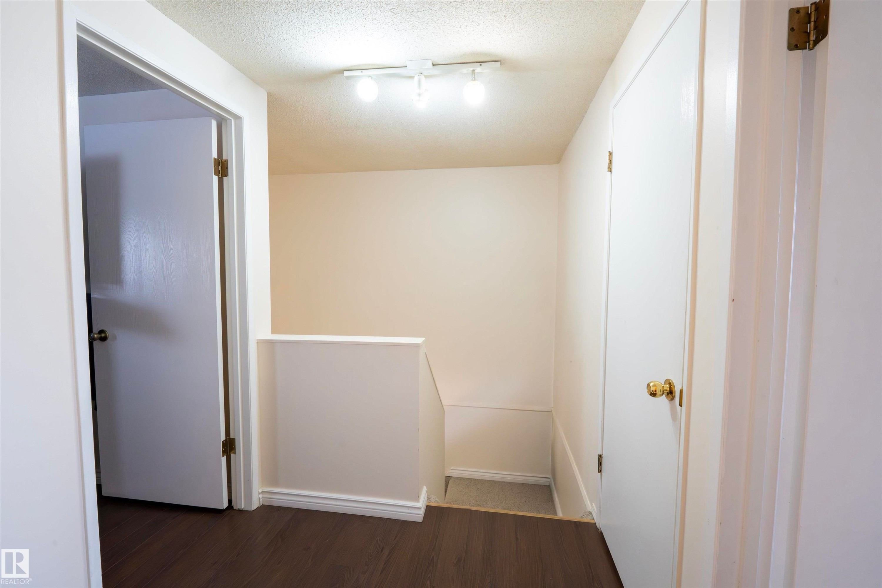This area features dark flooring, light-colored walls, and a track light fixture on the ceiling - 1728 37 Street, Edmonton, AB - Indoor Photo Showing Other Room