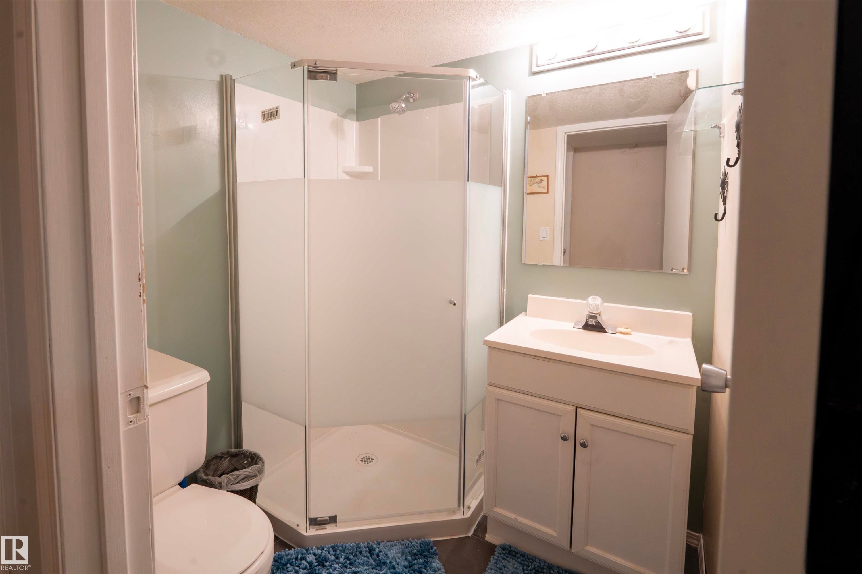 Bathroom featuring a corner shower with a glass enclosure, a white vanity with storage, and a mirror with overhead lighting - 1728 37 Street, Edmonton, AB - Indoor Photo Showing Bathroom