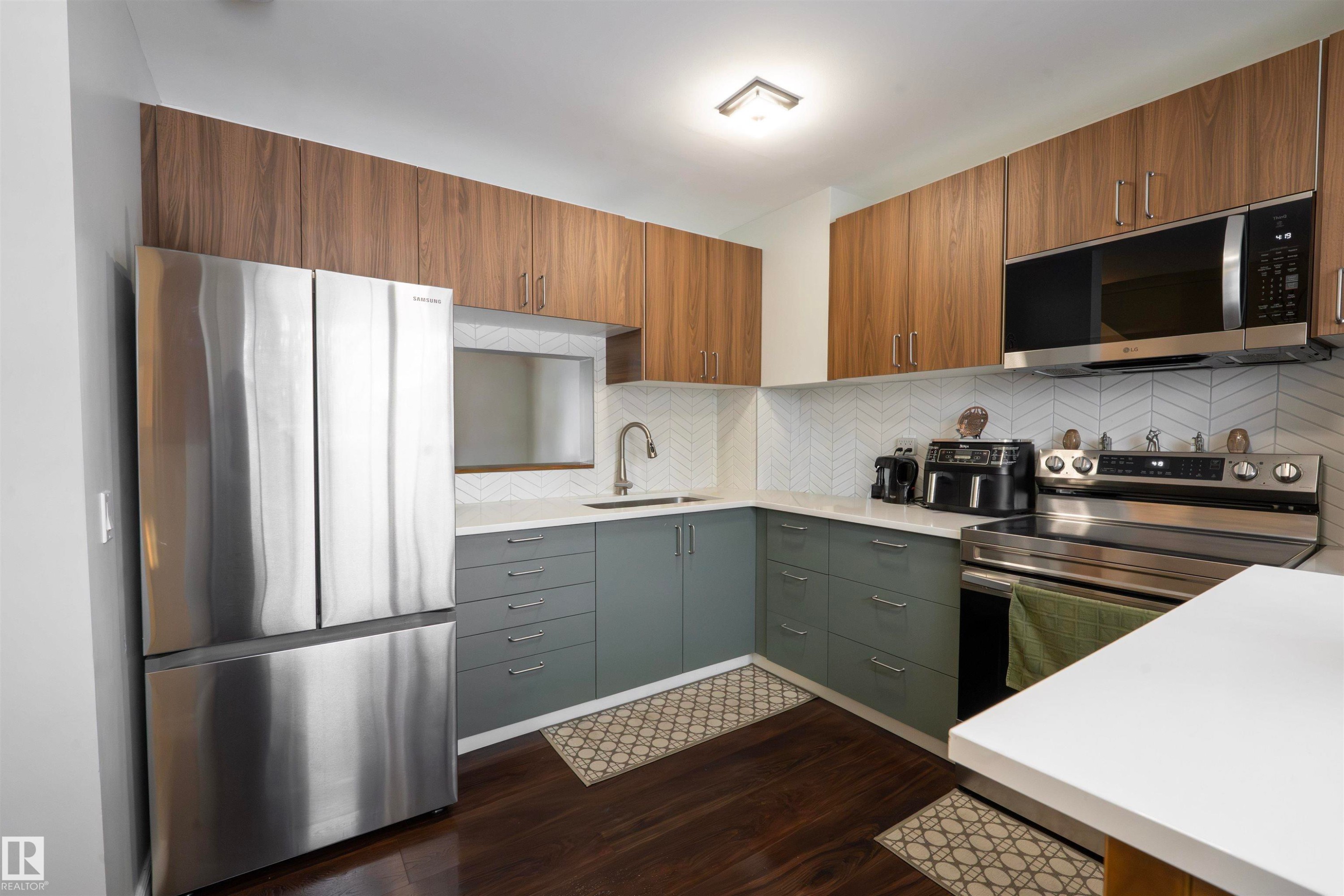 The kitchen features hardwood floors, stainless steel appliances, a white tile backsplash, and two-toned cabinetry - 1728 37 Street, Edmonton, AB - Indoor Photo Showing Kitchen With Upgraded Kitchen