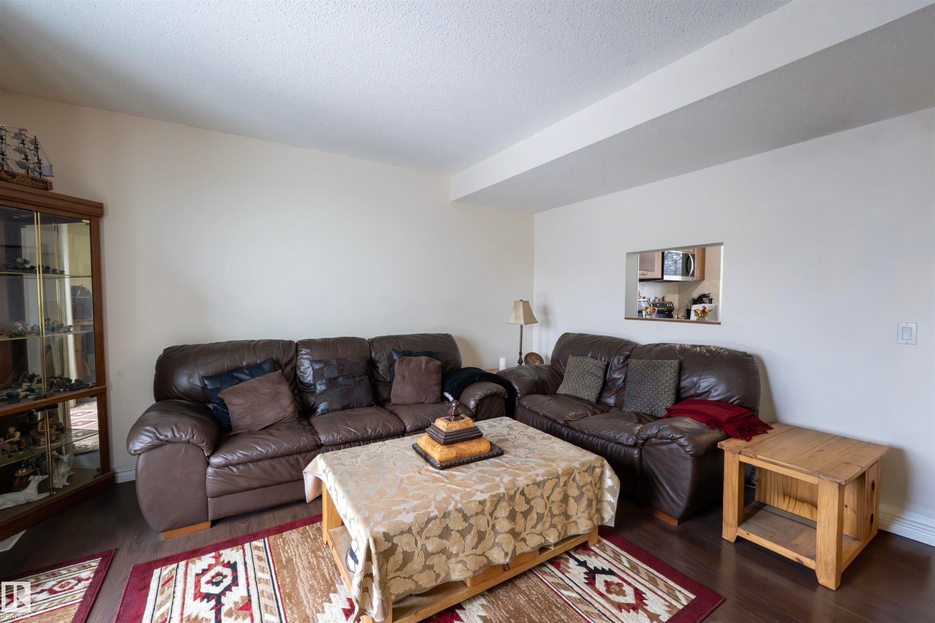 Living area featuring dark flooring, light-colored walls, and a pass-through window to an adjacent space - 1728 37 Street, Edmonton, AB - Indoor Photo Showing Living Room