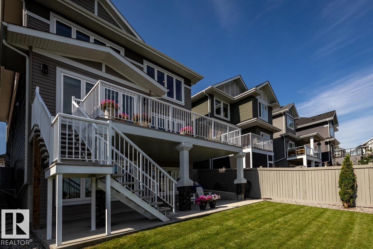 Rear exterior featuring a multi-level deck with white railings, direct backyard access, and a manicured lawn - 3419 Chickadee Drive, Edmonton, AB - Outdoor