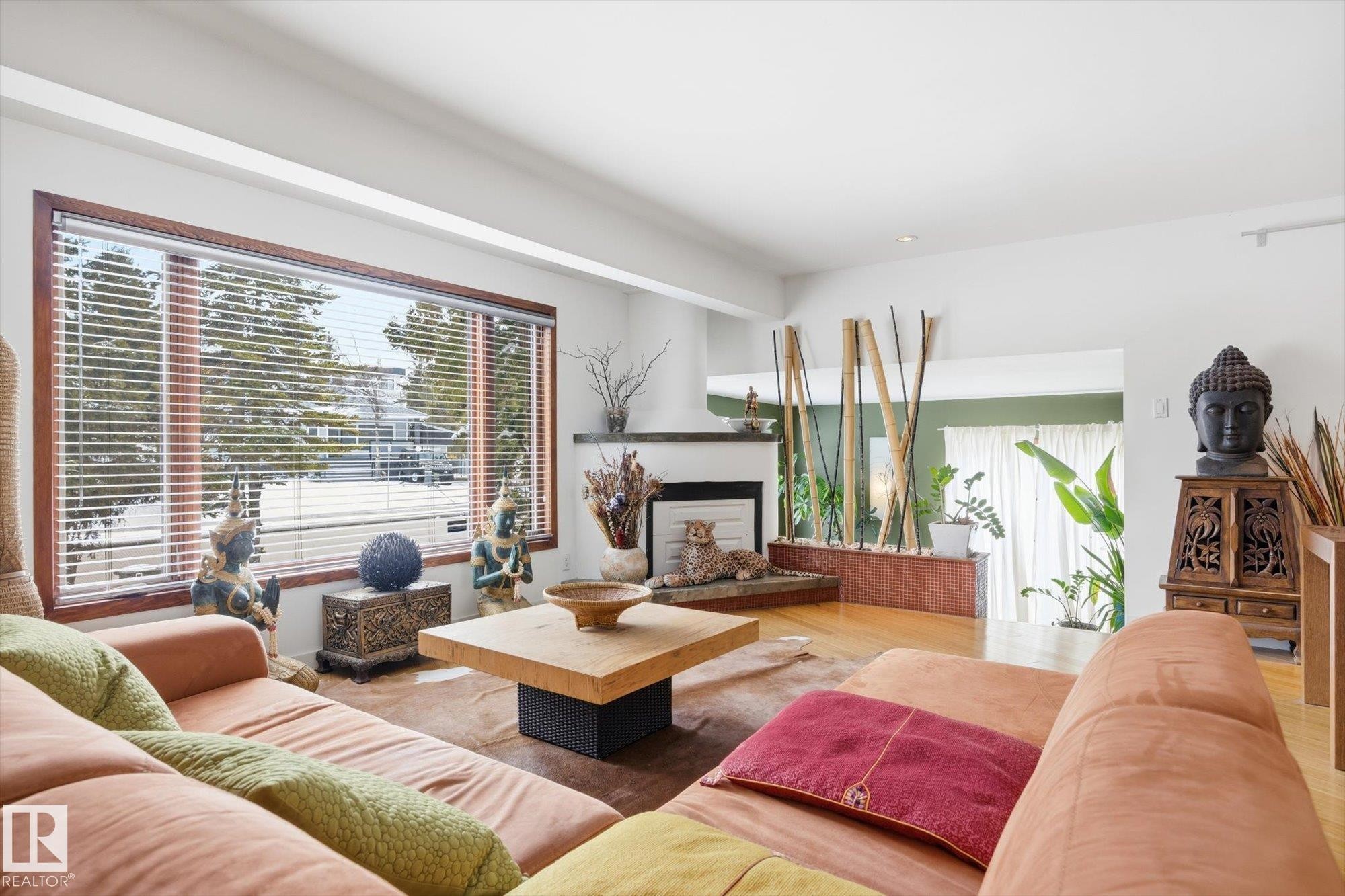 The living area features a large window with horizontal blinds, hardwood flooring, and a fireplace with a mantel - 11026 110 Avenue, Edmonton, AB - Indoor Photo Showing Living Room With Fireplace