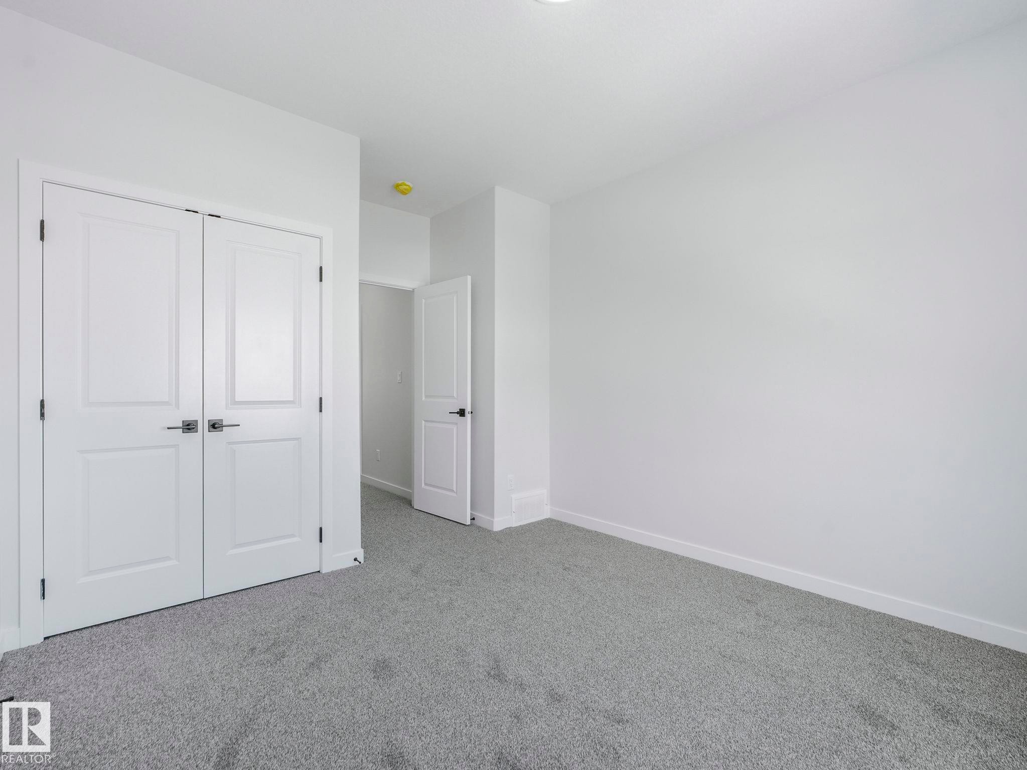 This room features plush grey carpeting, white walls, and bright white trim - 239 Kinglet Boulevard Nw, Edmonton, AB - Indoor Photo Showing Other Room