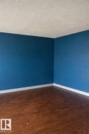 The room features rich brown flooring, blue walls, and white baseboards -
