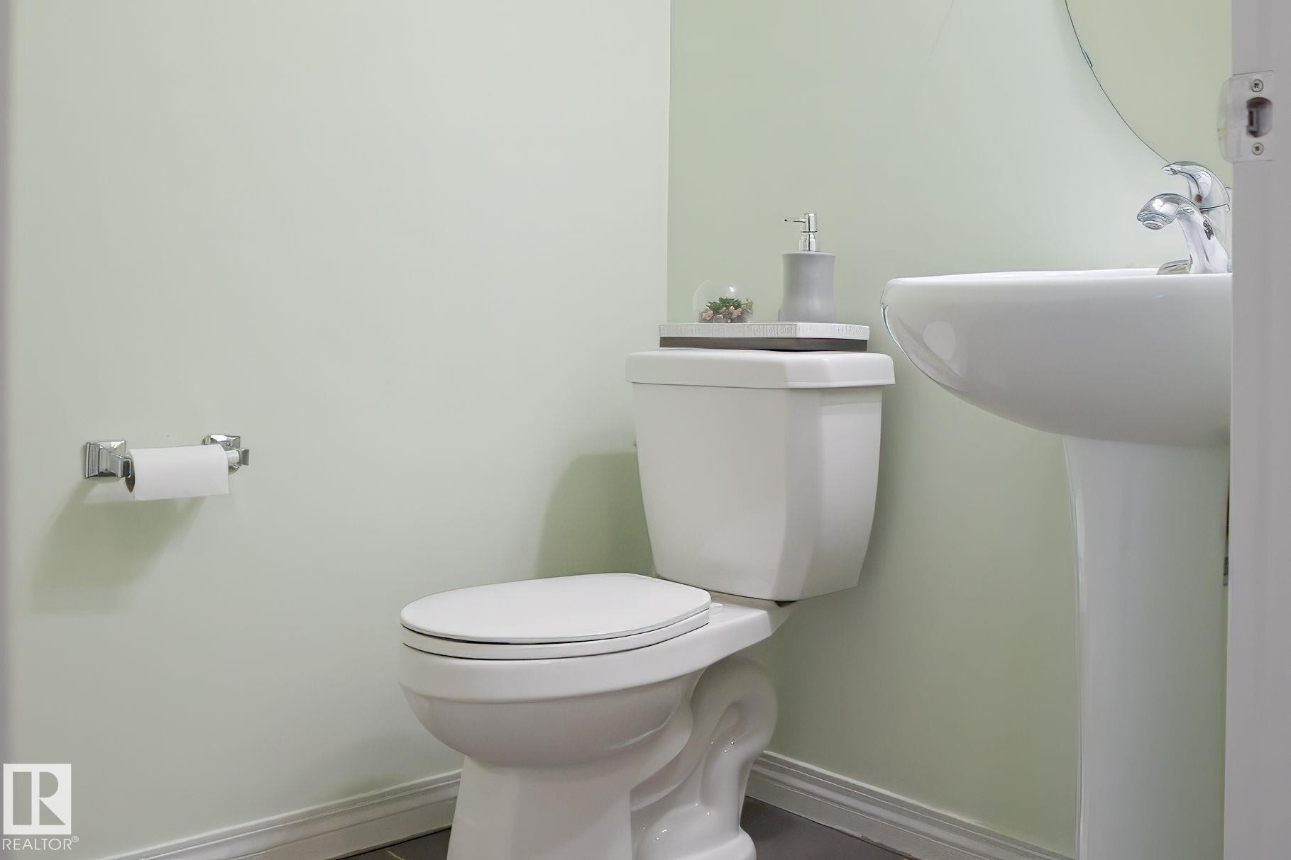 The bathroom features a white pedestal sink with a chrome faucet, and a white toilet - 4783 Crabapplle Run, Edmonton, AB - Indoor Photo Showing Bathroom