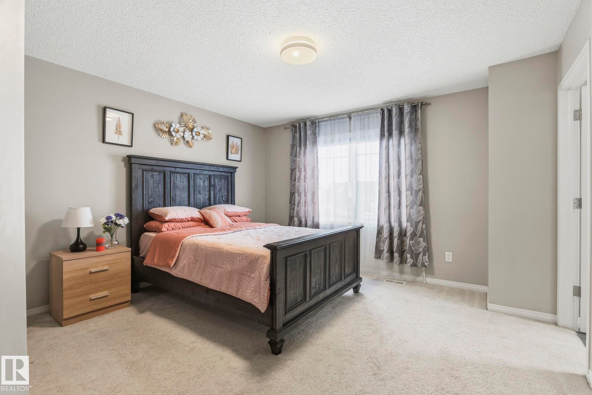 This room offers light-colored walls and carpeting, a window with curtains, and a ceiling light fixture - 4783 Crabapplle Run, Edmonton, AB - Indoor Photo Showing Bedroom