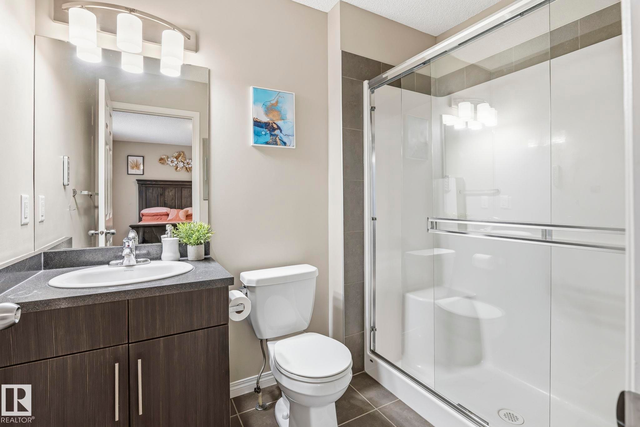 Bathroom featuring a vanity with a sink, a toilet, and a glass-enclosed shower - 4783 Crabapplle Run, Edmonton, AB - Indoor Photo Showing Bathroom